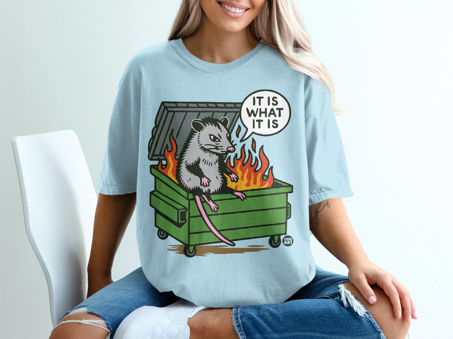 Opossum sitting in a burning dumpster with text "IT IS WHAT IT IS" in speech bubble.