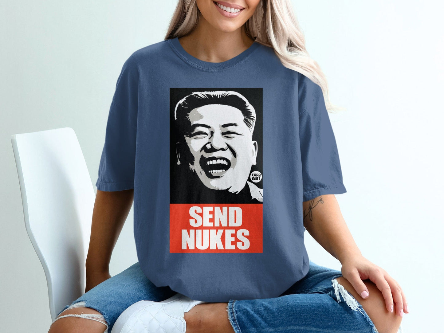 Dark blue t-shirt with a graphic of a laughing Kim Jong Un saying "SEND NUKES".