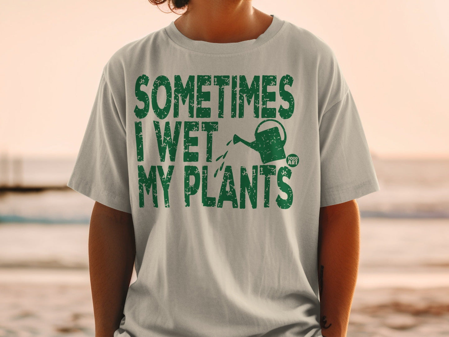 Green t-shirt with text "SOMETIMES I WET MY PLANTS" and a watering can.