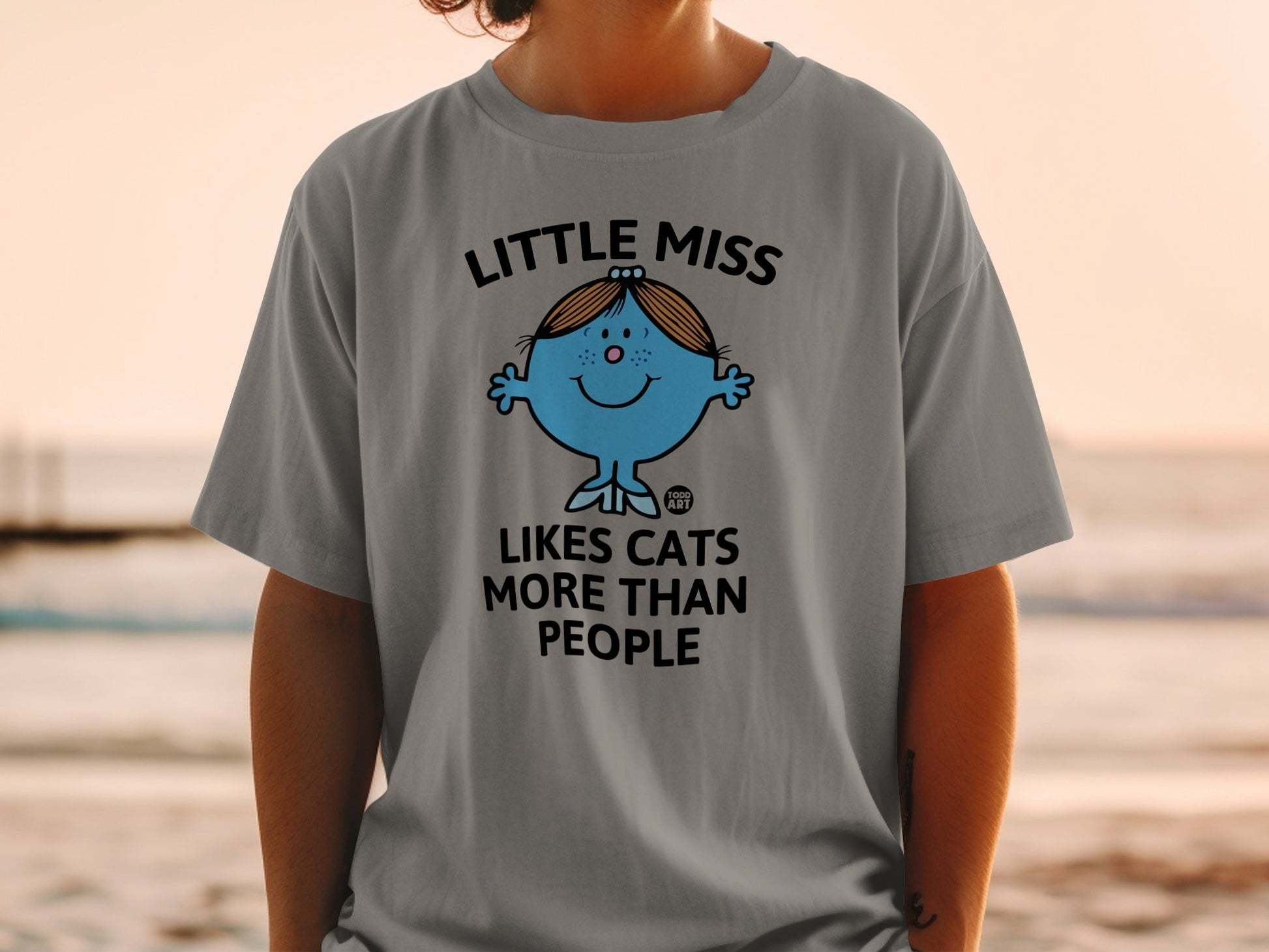 Little Miss character with text "Loves Cats More Than People" on a grey t-shirt.