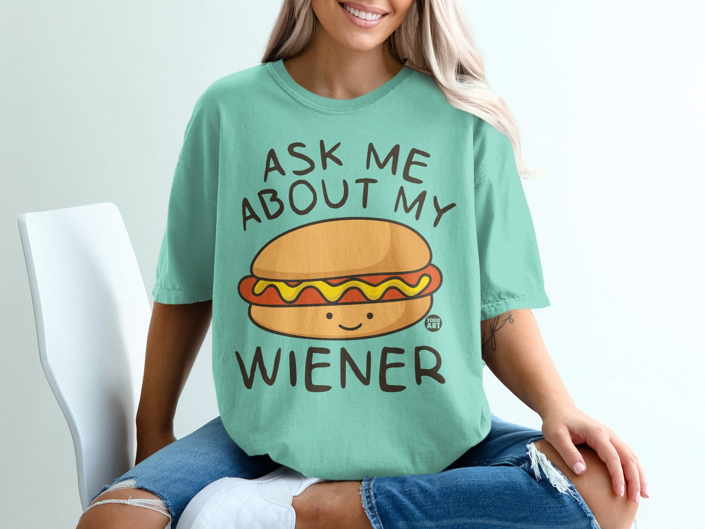 Teal t-shirt with "ASK ME ABOUT MY WIENER" and smiling hot dog graphic.