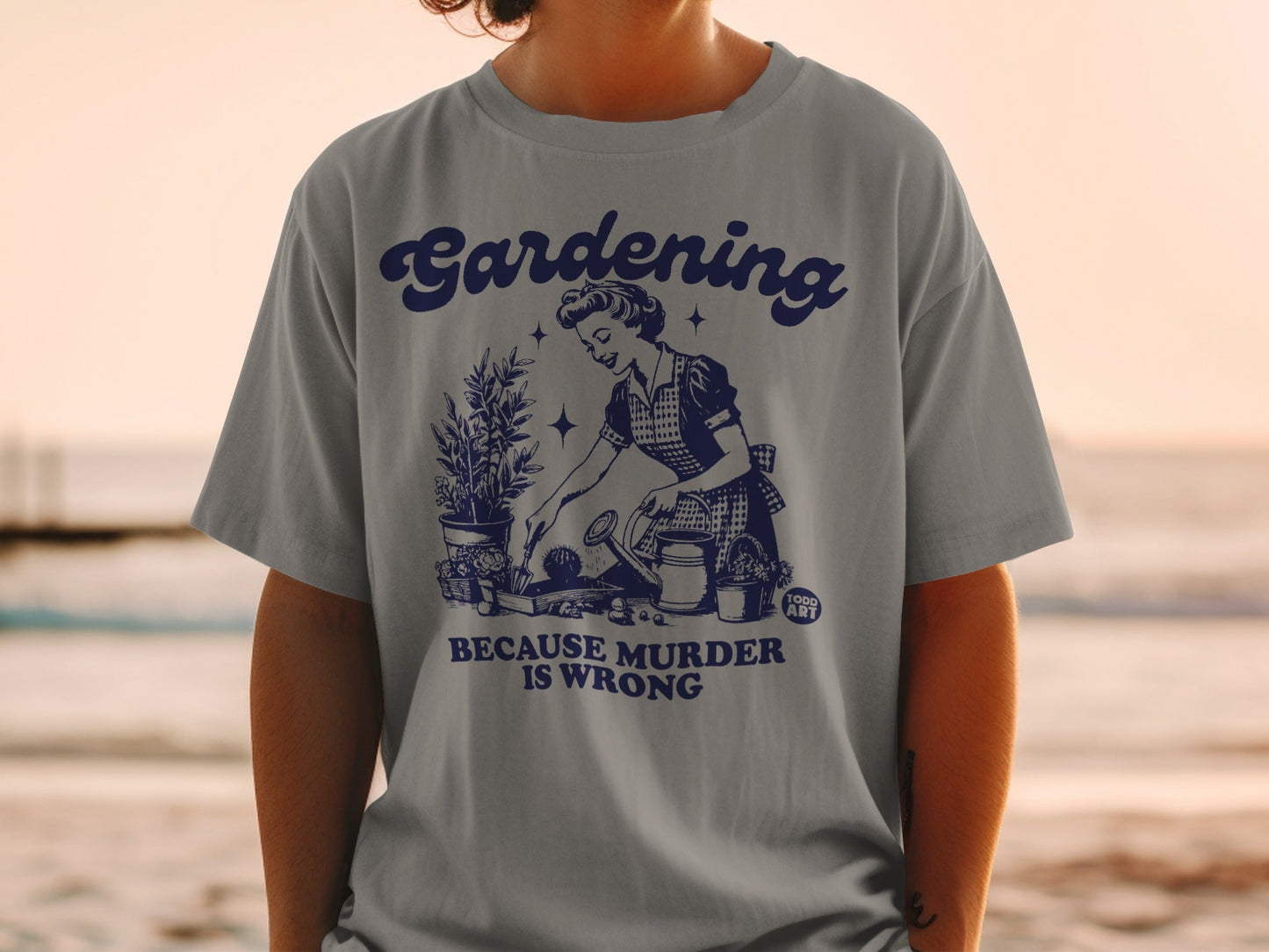 Gray t-shirt with vintage illustration of woman gardening and text "Gardening is Murder is Wrong".