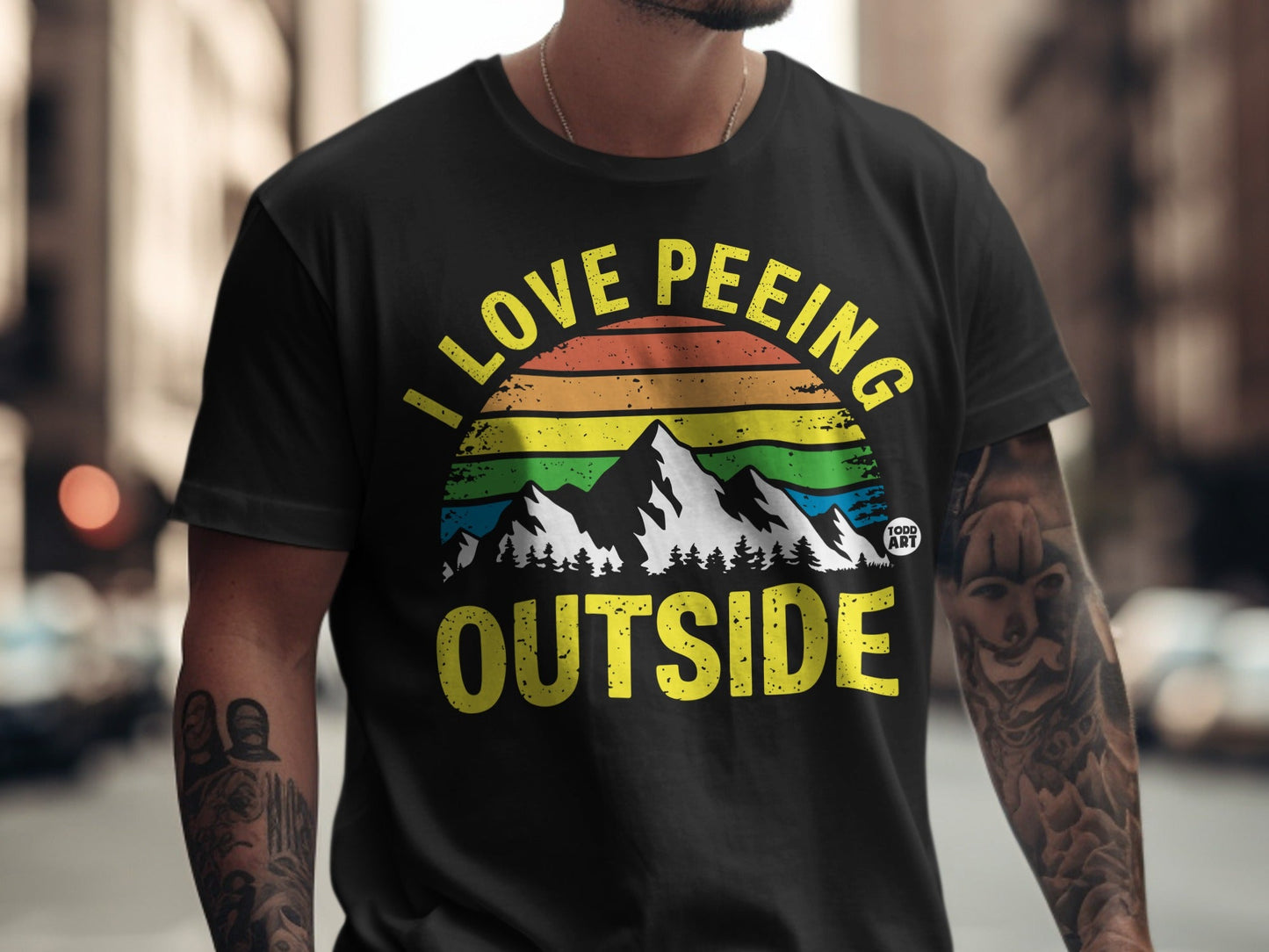 Black t-shirt with rainbow mountains and "I love peeing outside" text.