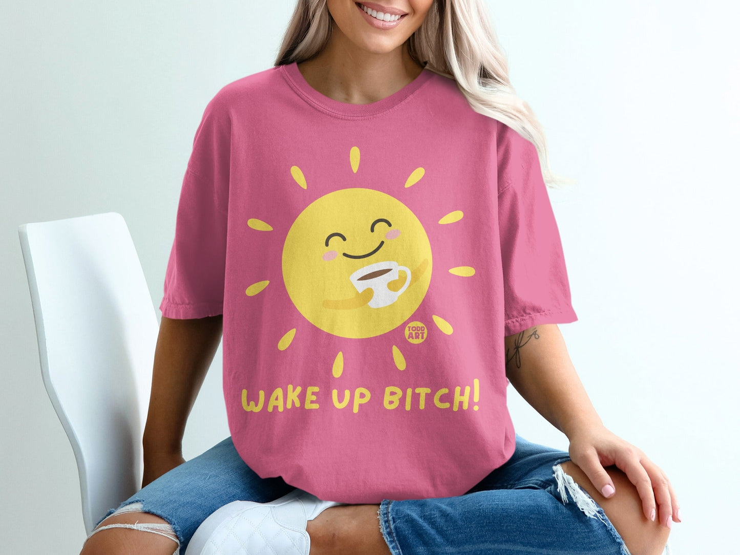Pink t-shirt with smiling sun holding coffee cup, text "WAKE UP BITCH!".