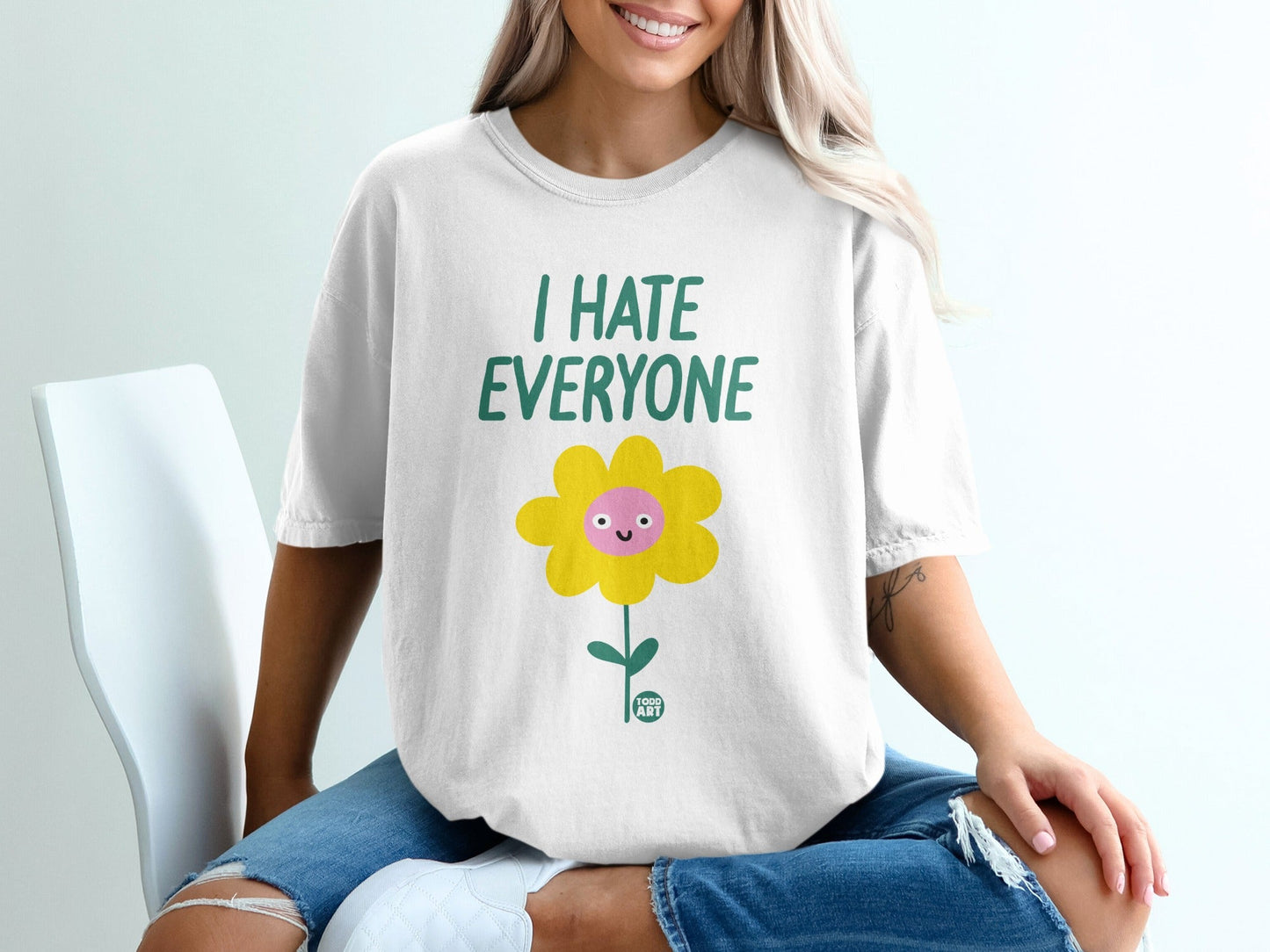 White t-shirt with a smiling cartoon flower and "I HATE EVERYONE" text.