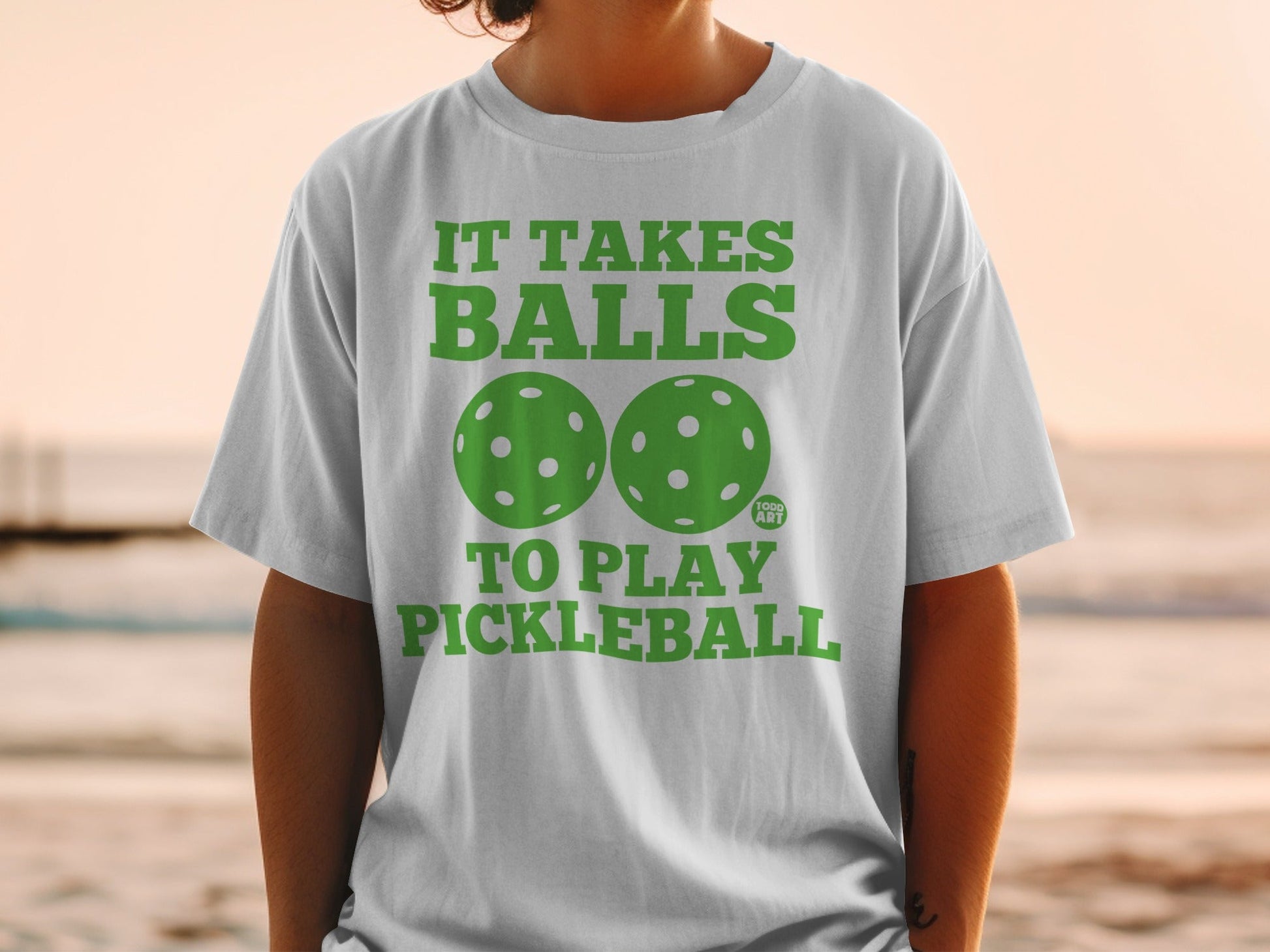 White t-shirt with "IT TAKES BALLS TO PLAY PICKLEBALL" and green pickleballs.