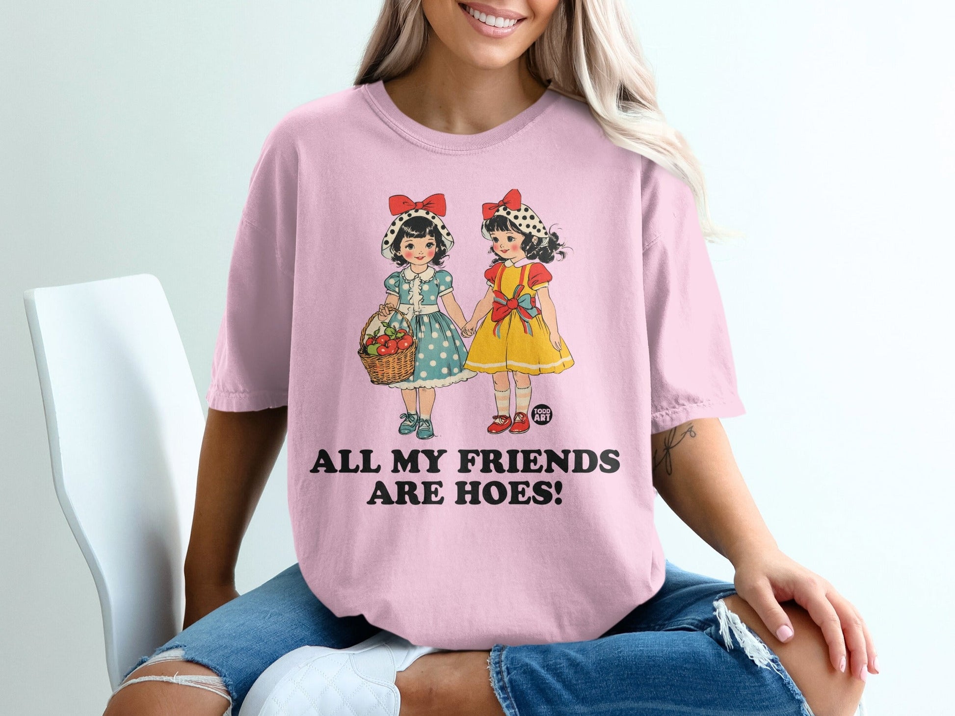 Pink t-shirt with graphic of two girls, basket, and text "ALL MY FRIENDS ARE HOES!".