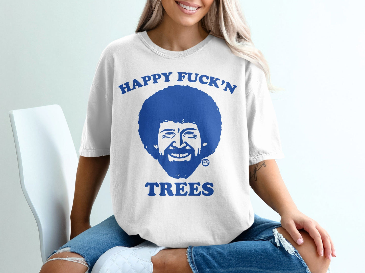 White t-shirt with Bob Ross graphic and text "Happy Fuck'n Trees".