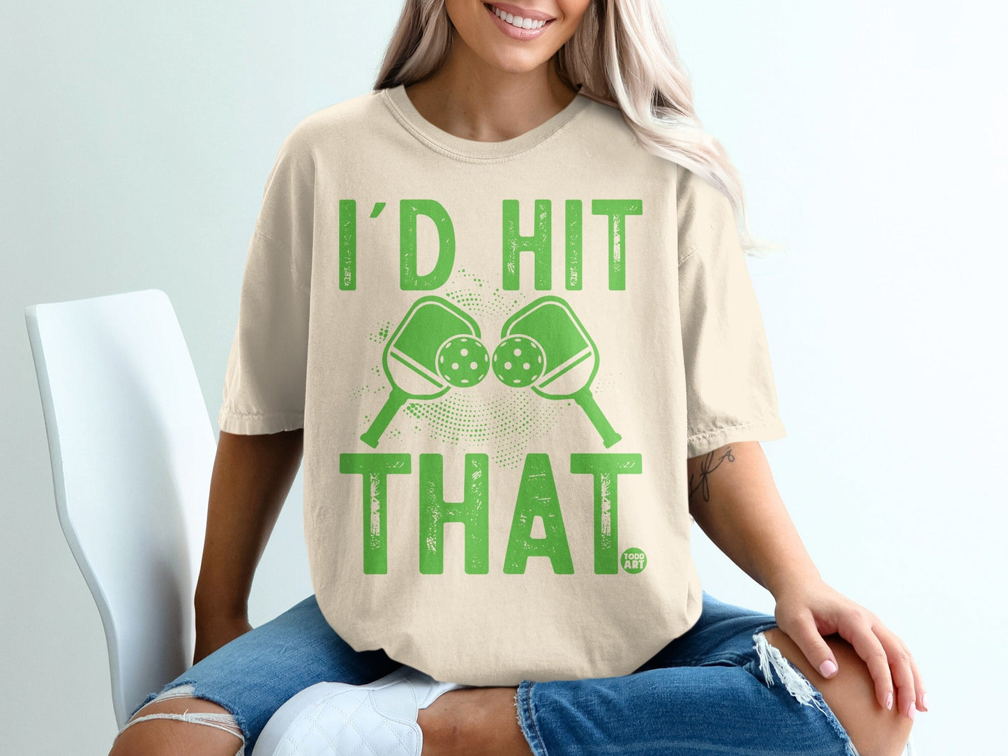 Cream t-shirt with "I'd Hit That" and crossed pickleball paddles graphic.
