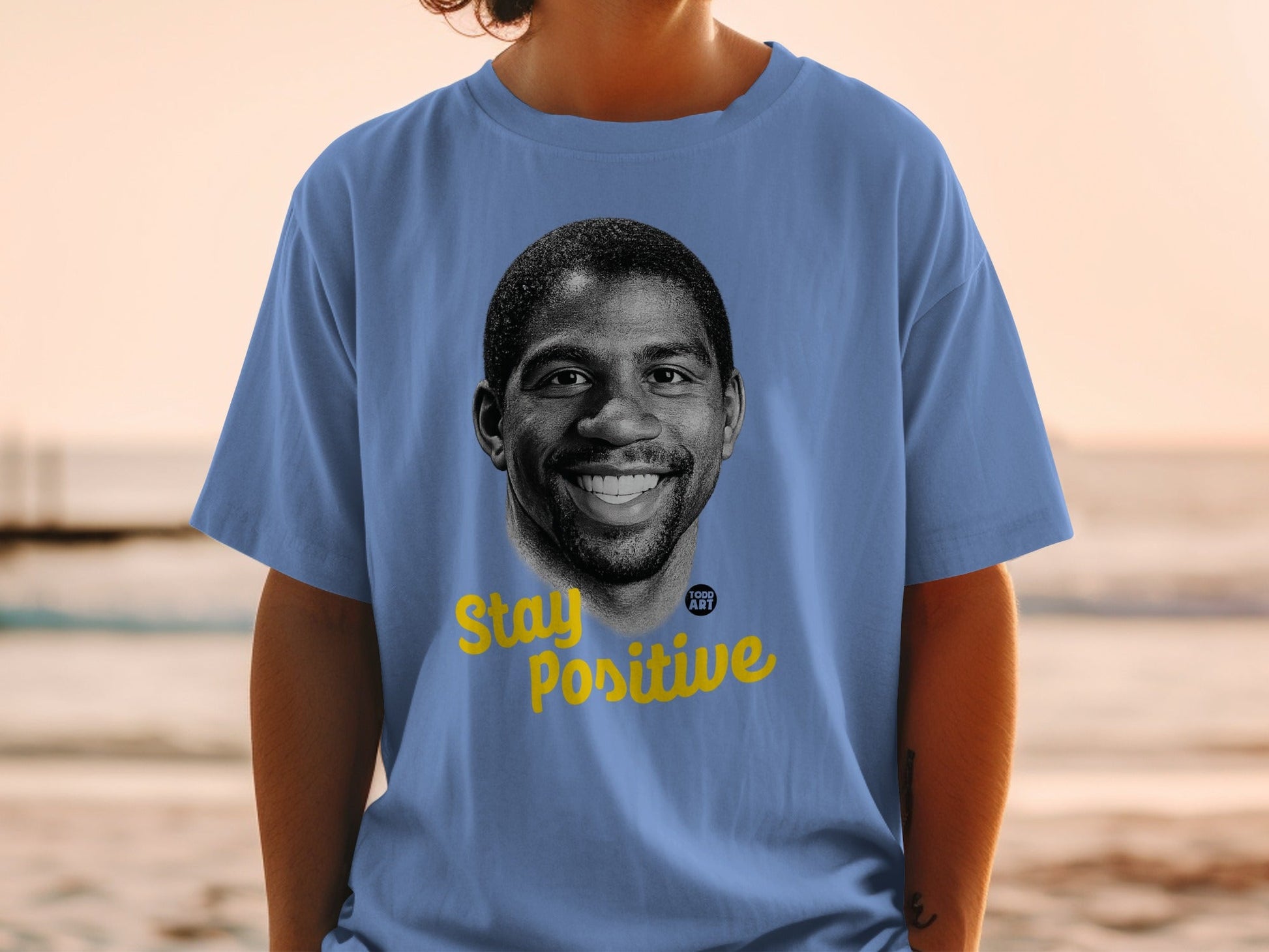 Blue t-shirt with a portrait of Magic Johnson and "Stay Positive" text.