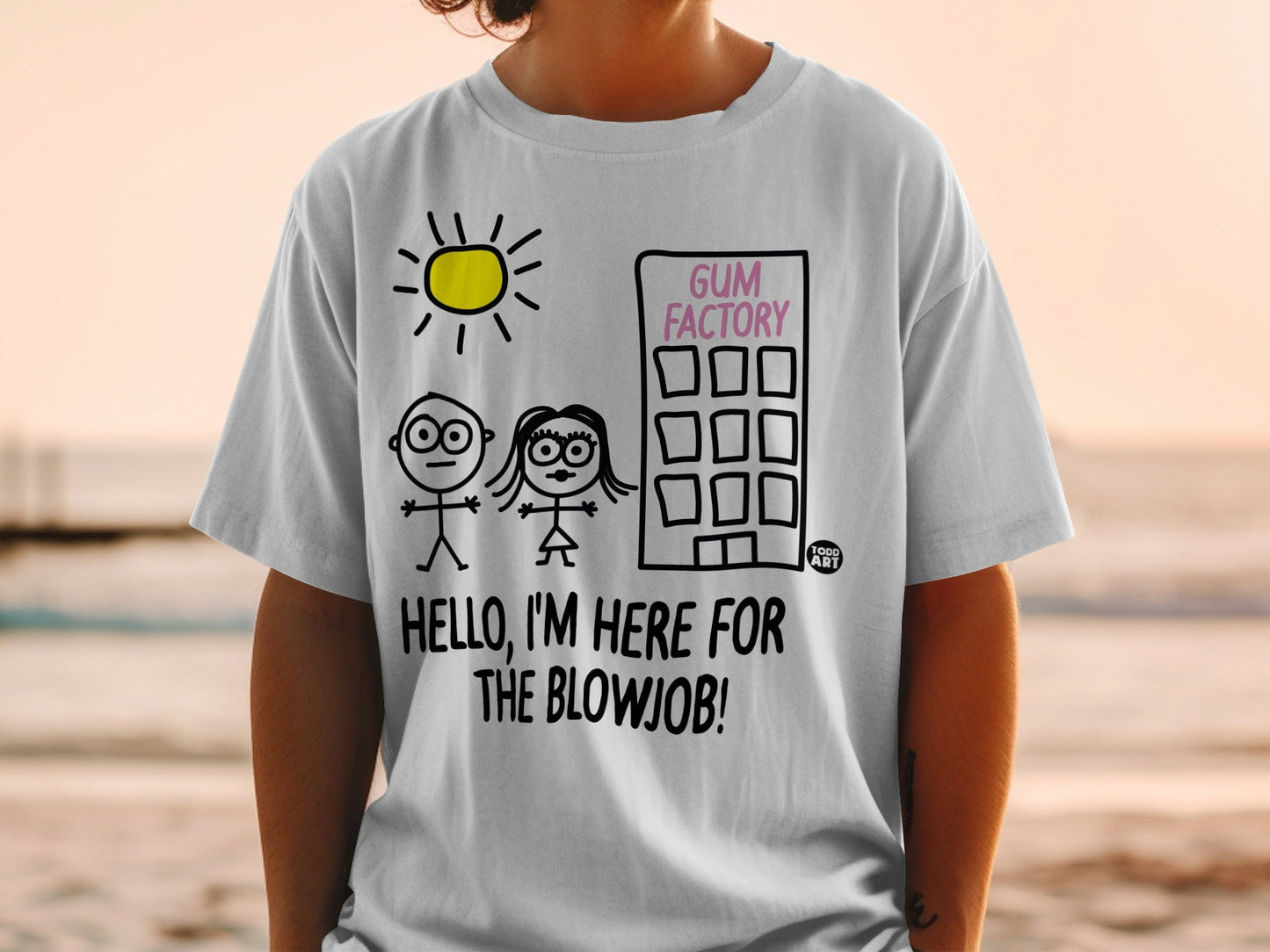 White t-shirt with cartoon figures, a building labeled "GUM FACTORY", and text "HELLO, I'M HERE FOR THE BLOWJOB!".
