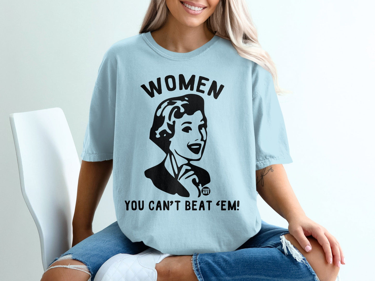 Light blue t-shirt with "WOMEN YOU CAN'T BEAT 'EM!" slogan and retro illustration.