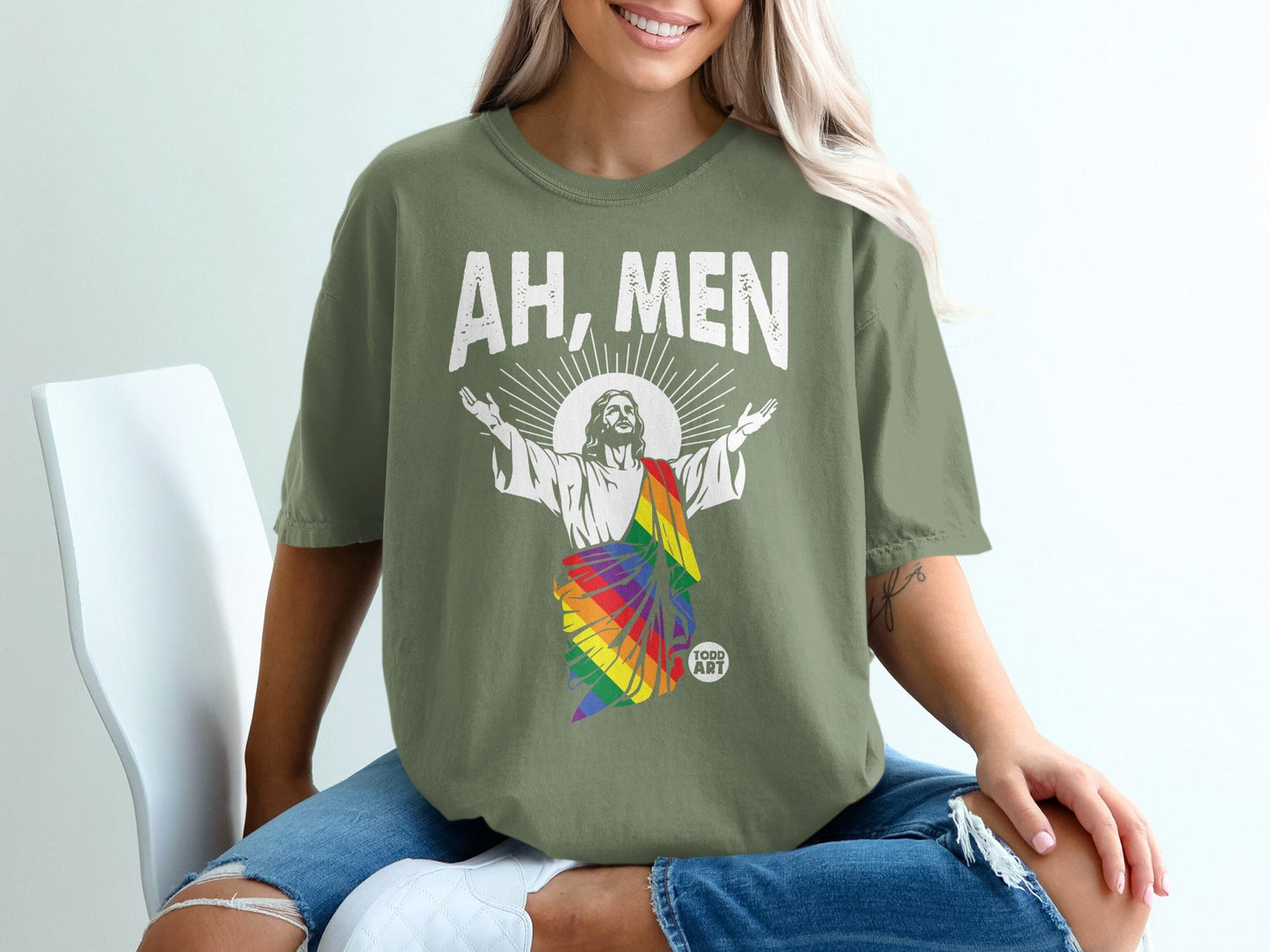 Jesus in rainbow flag colors with arms raised, wearing "AH, MEN" shirt.