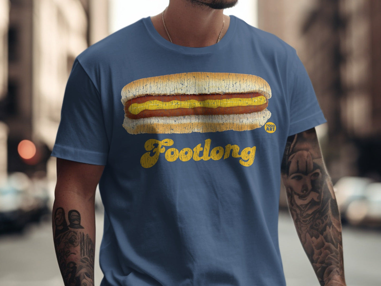 Blue t-shirt with a graphic of a footlong hot dog with mustard and "Footlong" text.