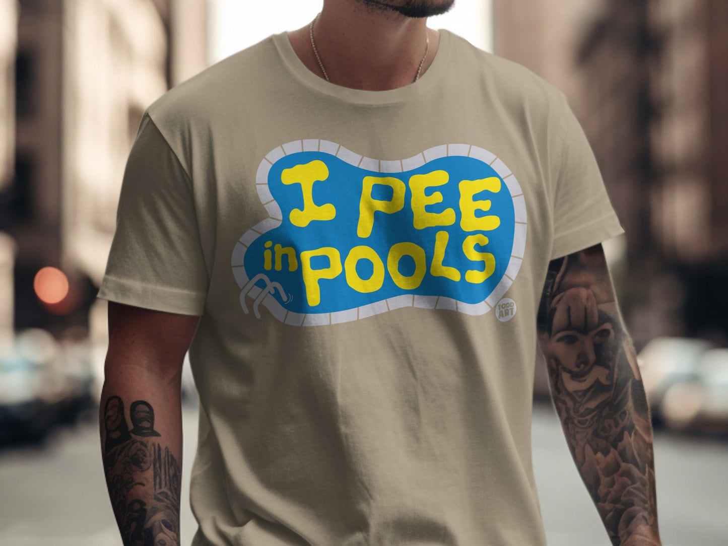 Tan t-shirt with yellow text that reads "I PEE in POOLS" in a swimming pool shape.