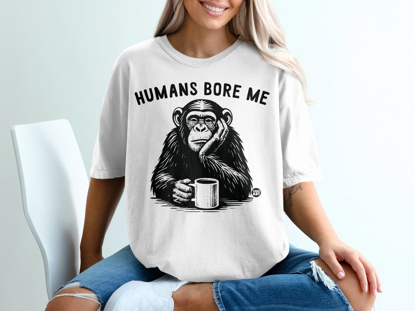 Chimpanzee wearing a t-shirt that says "Humans Bore Me" holding a coffee mug.