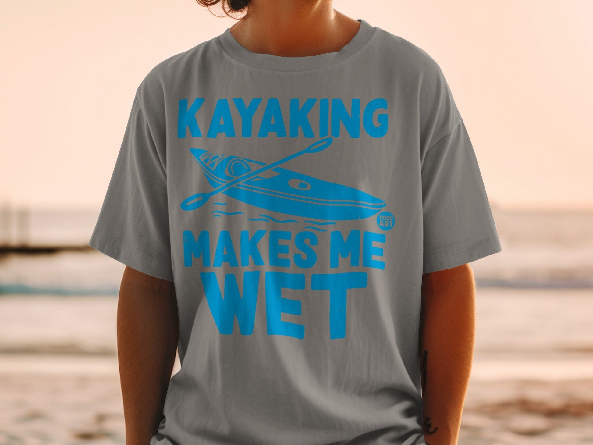 Gray t-shirt with blue text and graphic reading "Kayaking Makes Me Wet".