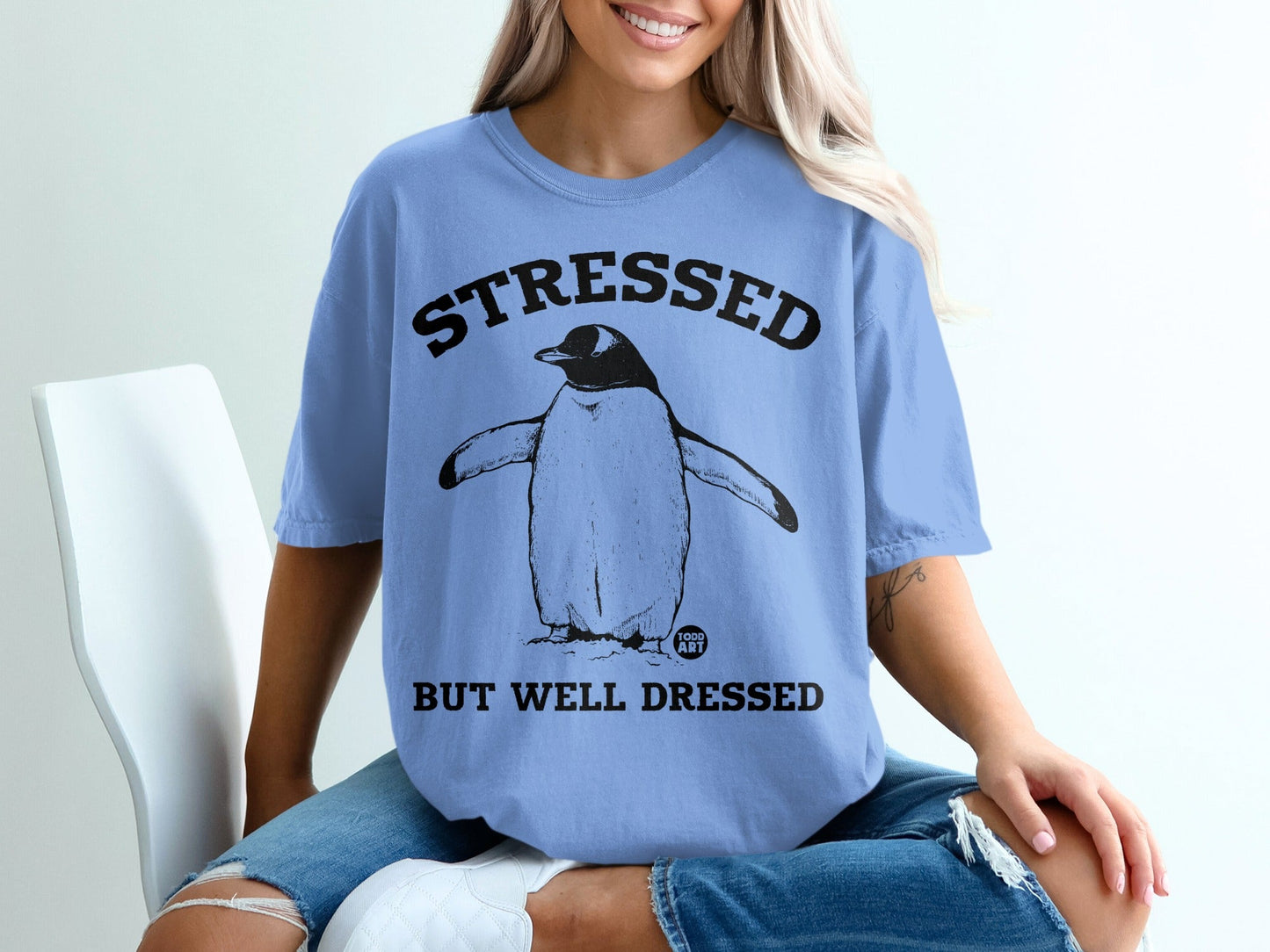 Blue t-shirt with a penguin and text "STRESSED BUT WELL DRESSED".