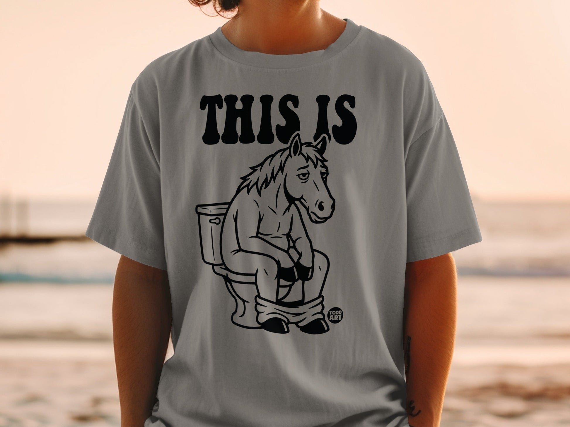 T-shirt with a cartoon horse sitting on a toilet, text "THIS IS".
