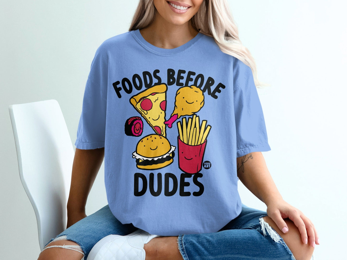 Light blue t-shirt with cartoon "Foods Before Dudes" graphic featuring pizza, burger, fries, and chicken.