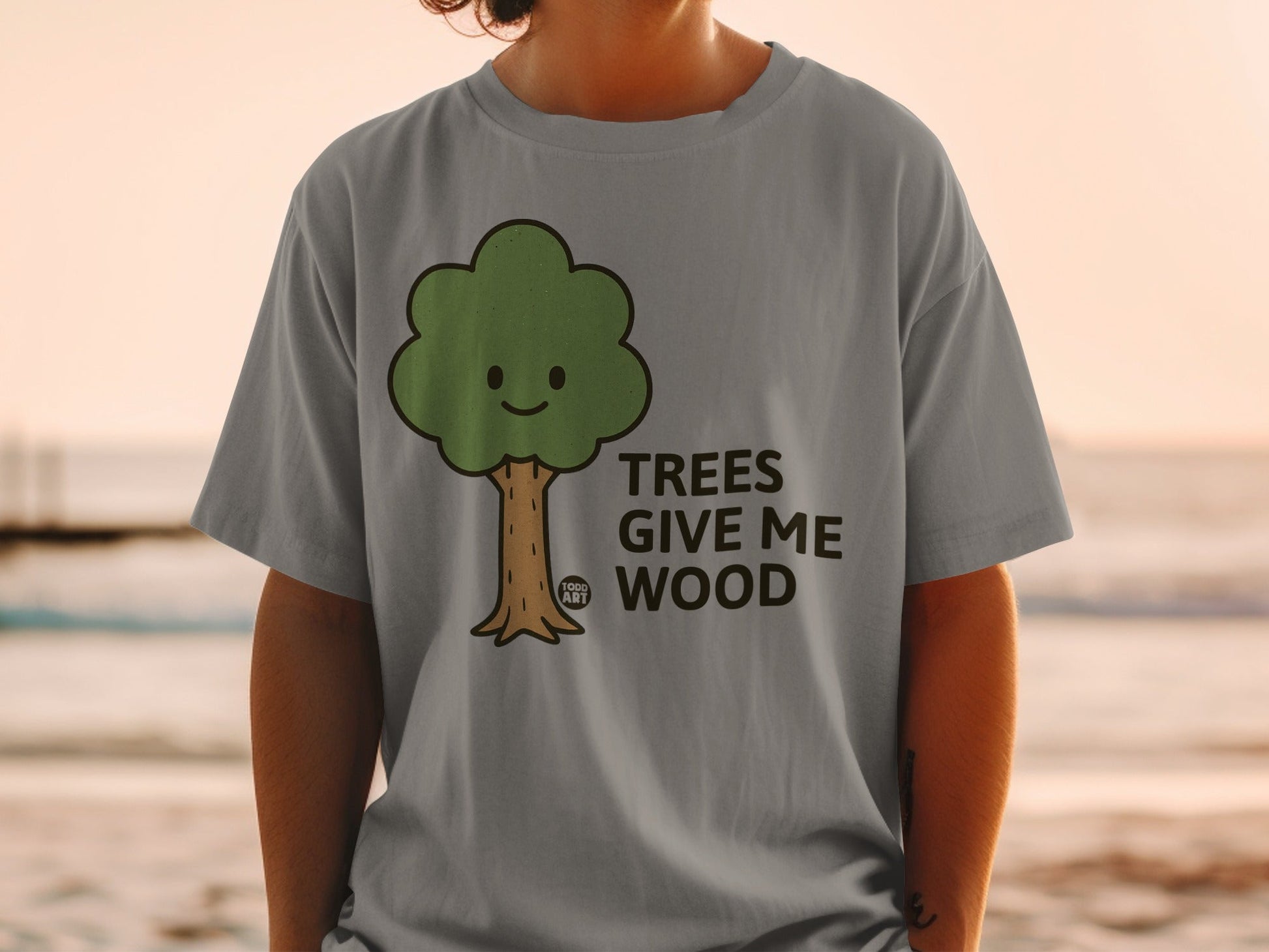 Grey t-shirt with a smiling cartoon tree and the text "TREES GIVE ME WOOD".