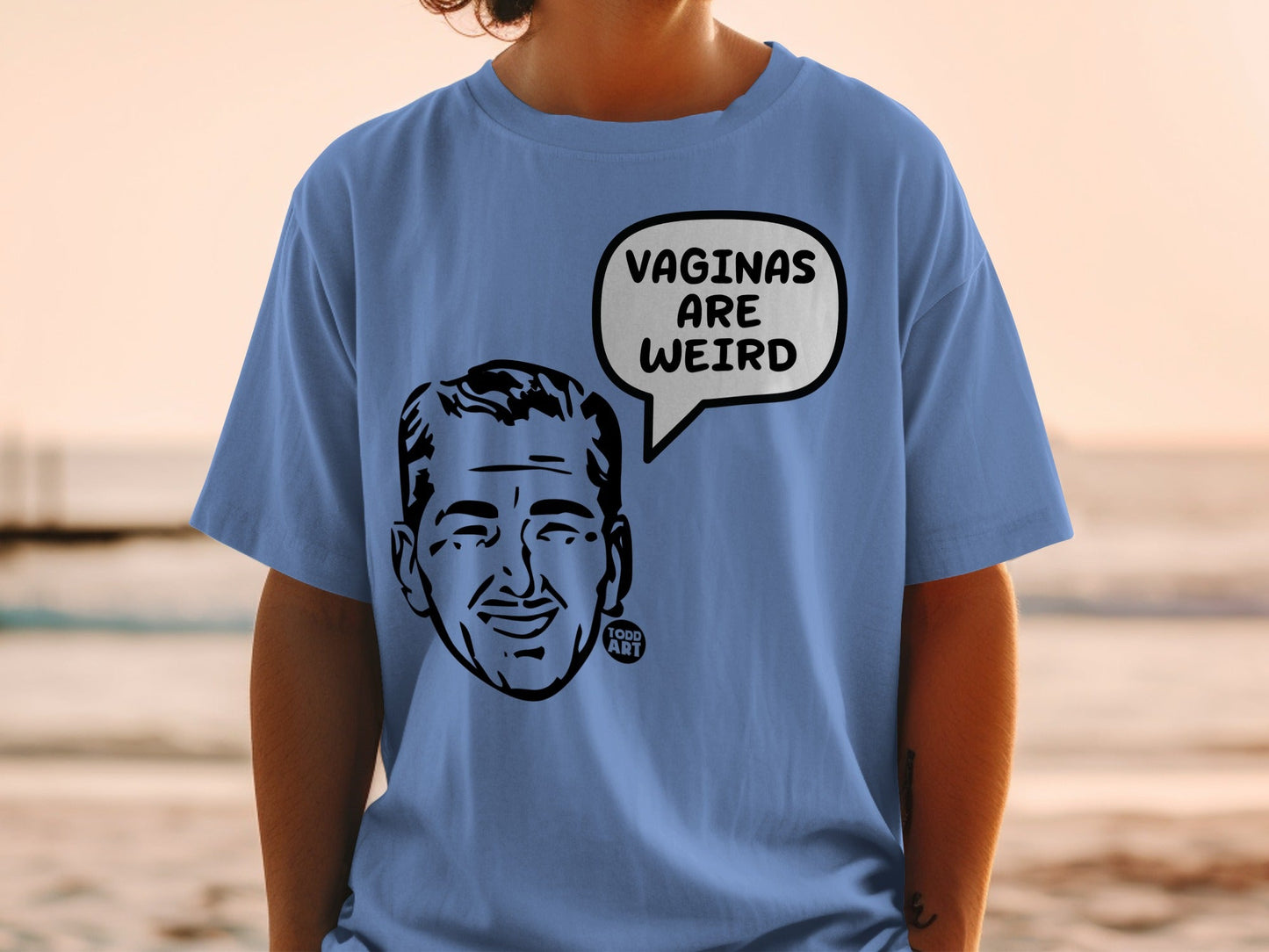Blue t-shirt with a black and white cartoon face in a speech bubble that says "VAGINAS ARE WEIRD".