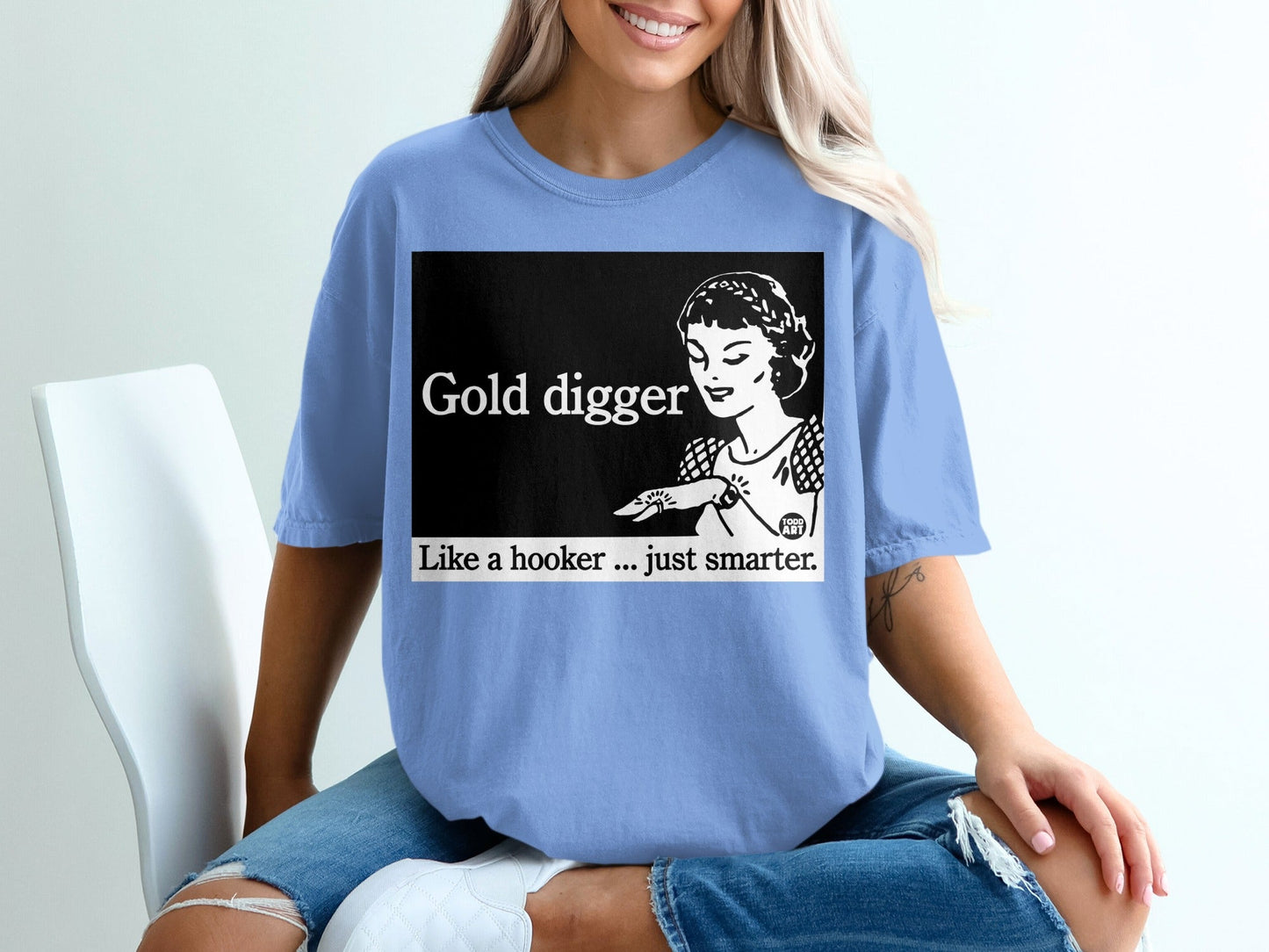 Woman wearing a light blue t-shirt with "Gold digger. Like a hooker... just smarter." text.