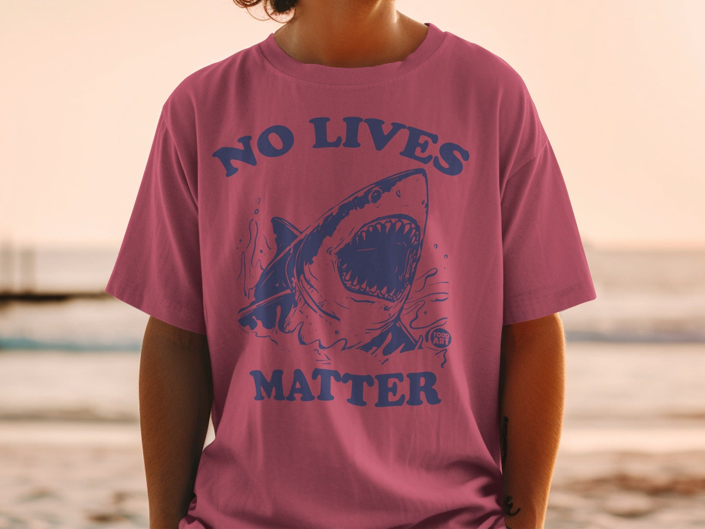 Pink t-shirt with graphic of a shark with text "NO LIVES MATTER".
