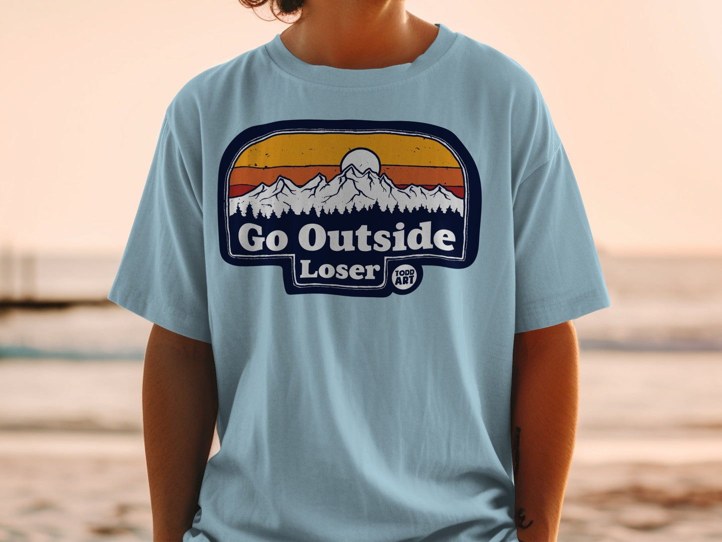 T-shirt with "Go Outside Loser" text and mountain sunset graphic.
