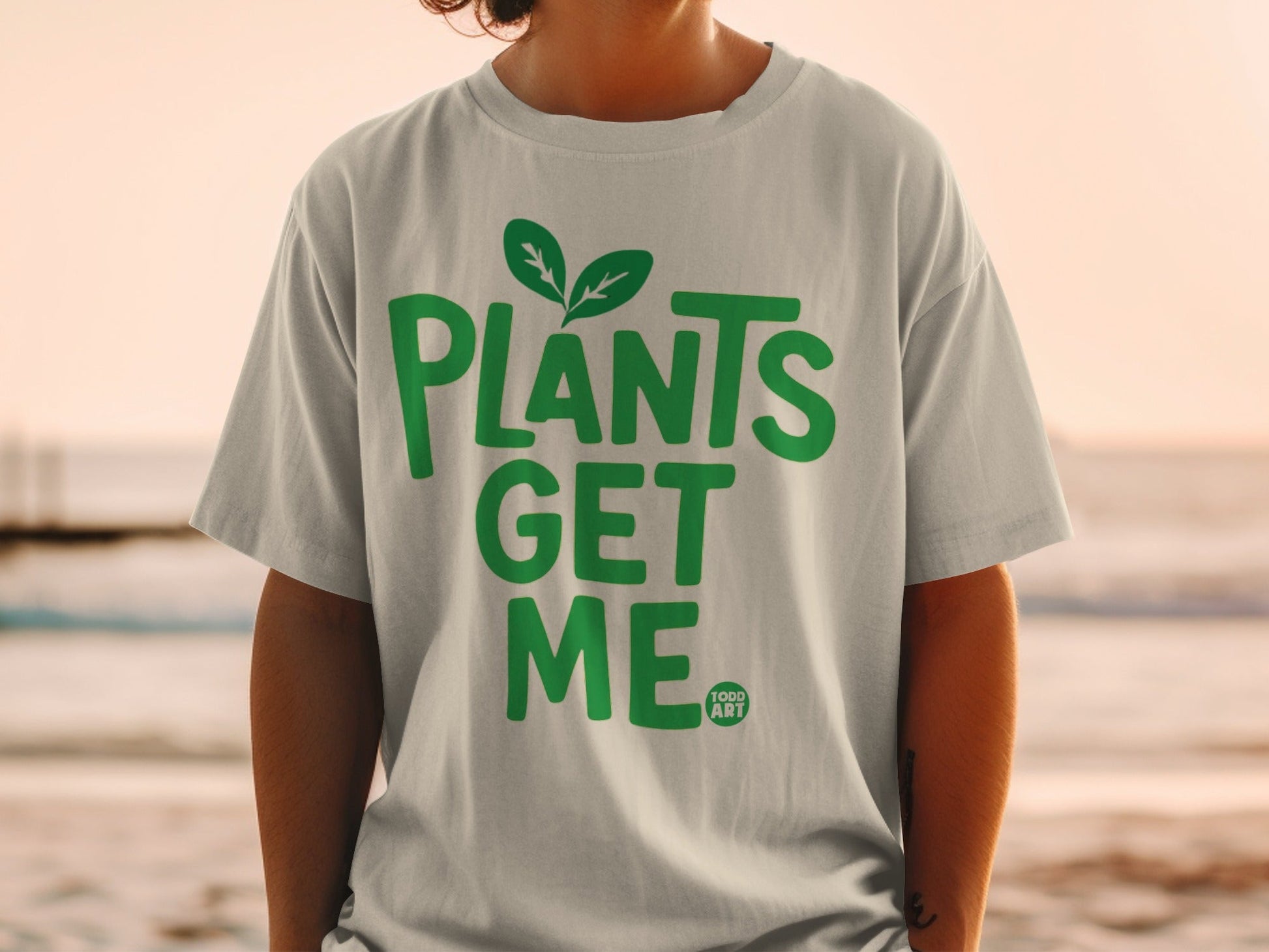 Green t-shirt with "PLANTS GET ME" text and a small leaf logo.