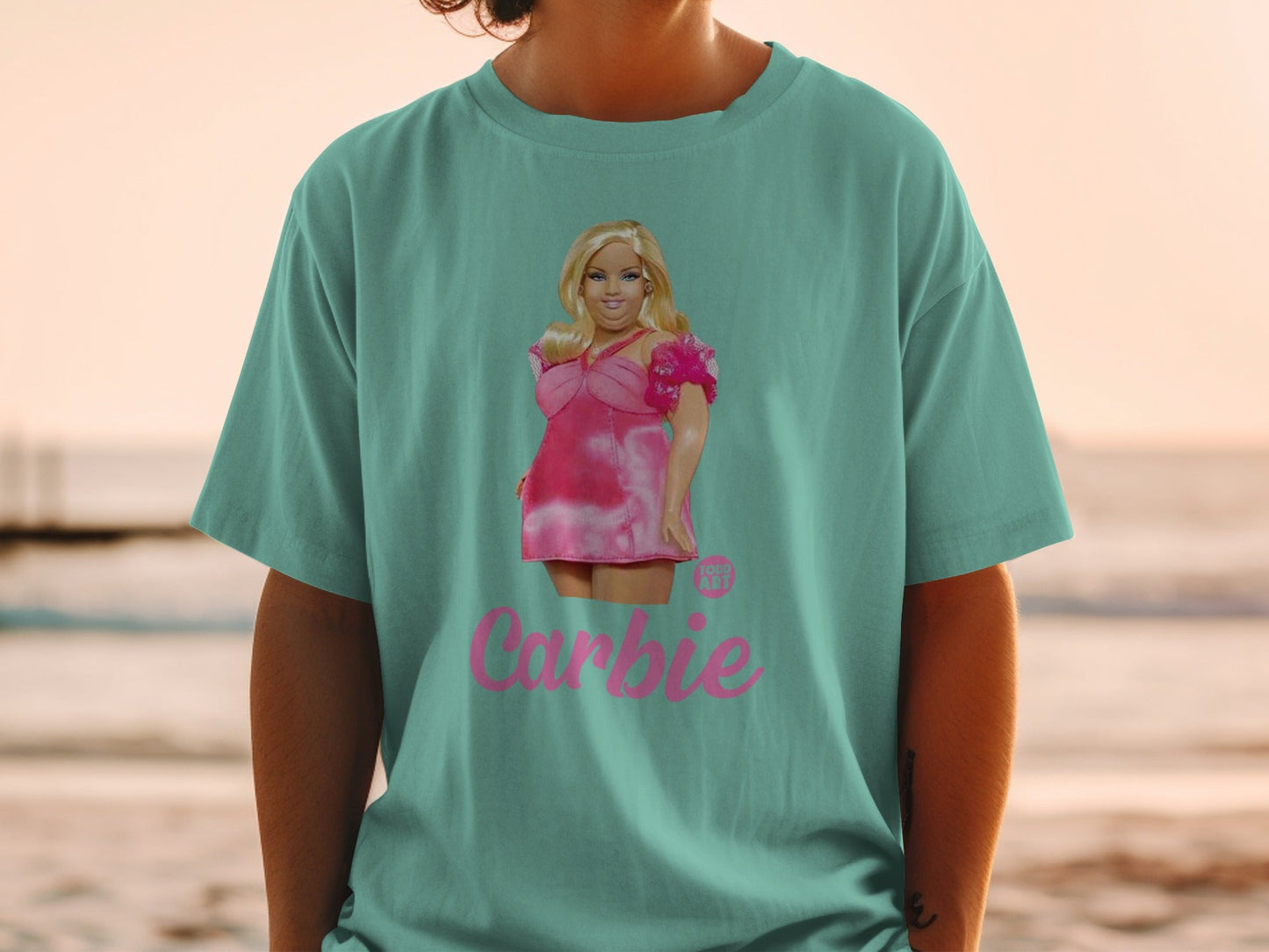 Barbie t-shirt with pink dress graphic on teal shirt.