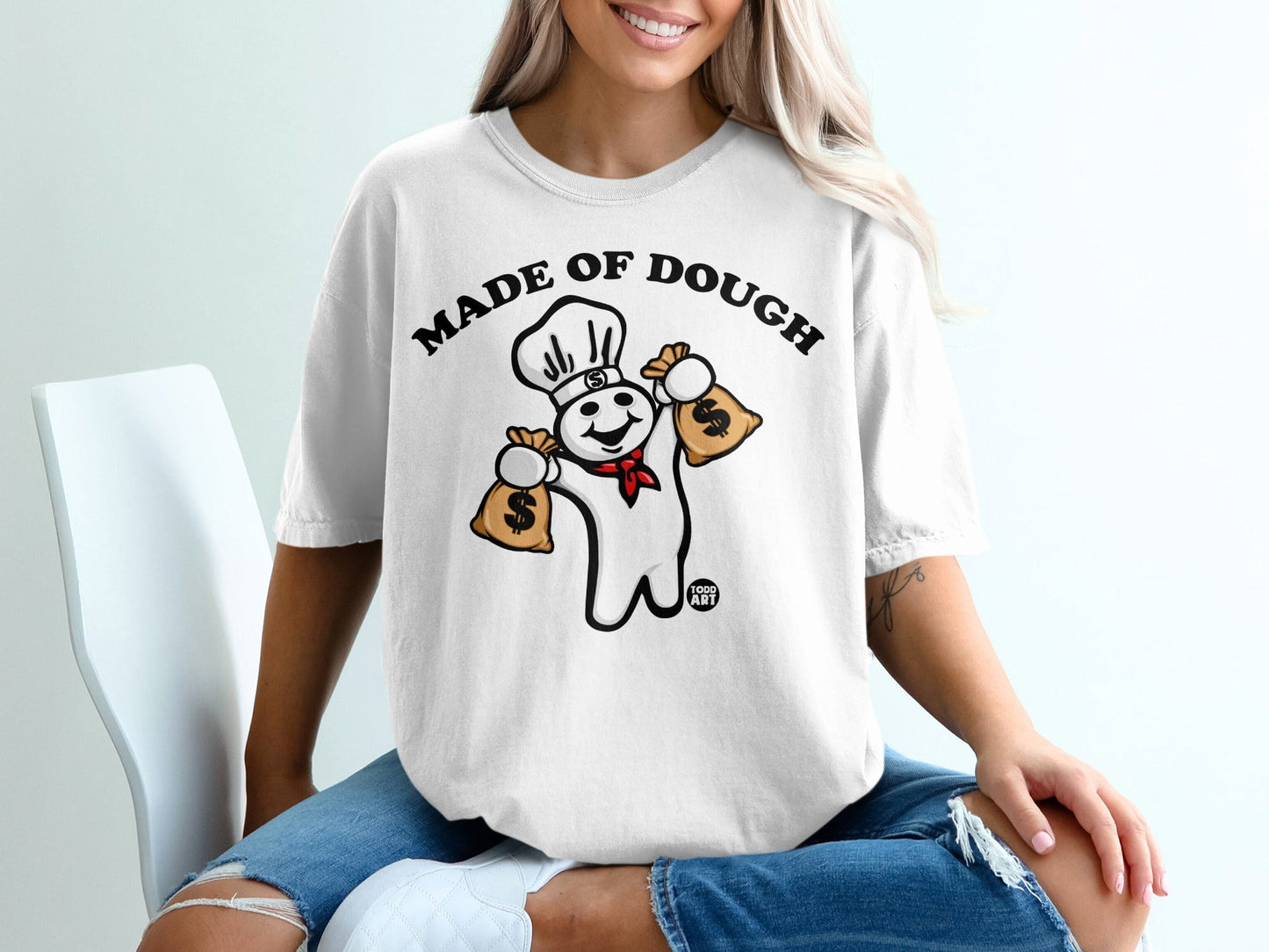 White t-shirt with chef character holding money bags, "Made of Dough" text.