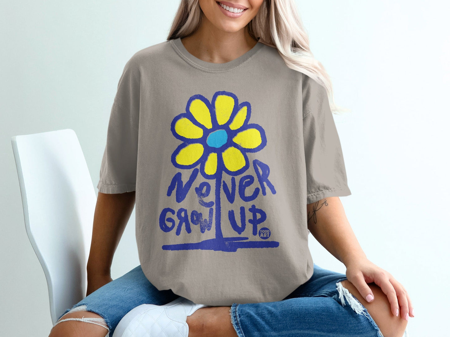 T-shirt with yellow flower graphic and "Never Grow Up" text.