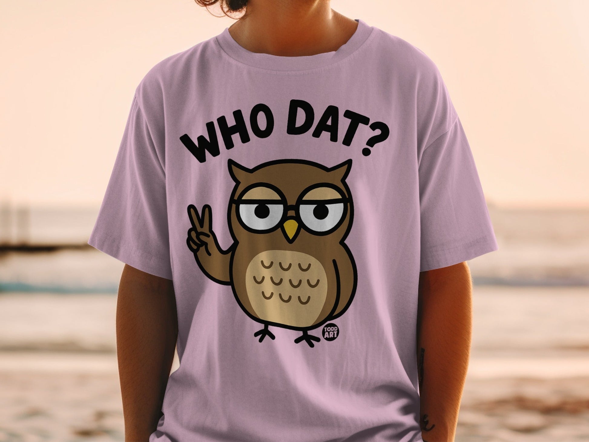 Lavender t-shirt with cartoon owl wearing glasses making peace sign.