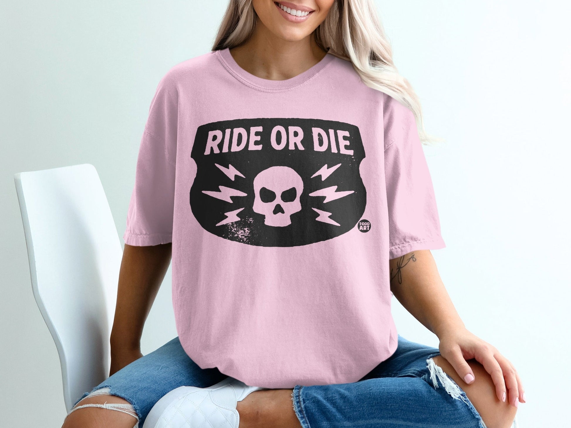 Pink t-shirt with black "RIDE OR DIE" shield graphic and lightning bolts.