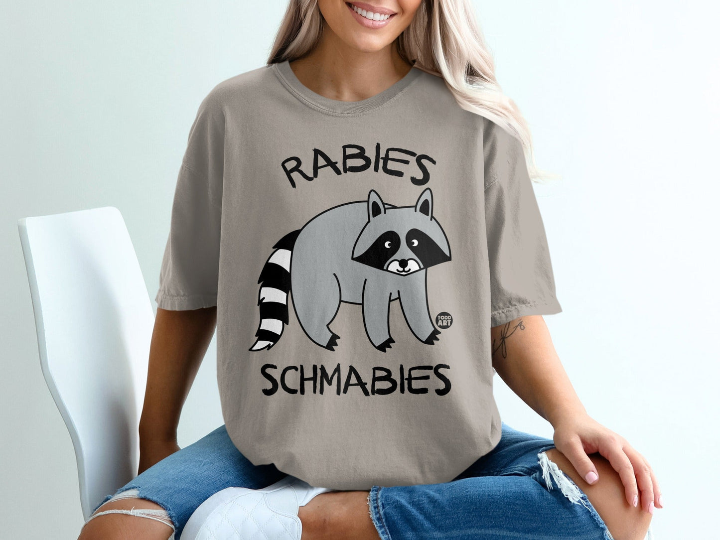 T-shirt with cartoon raccoon and text "RABIES SCHMABIES".