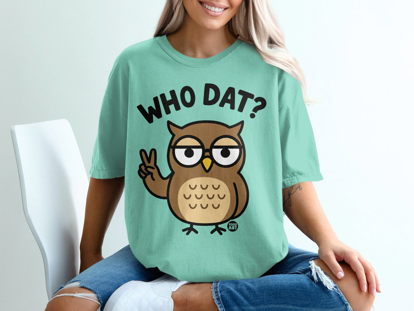 Teal t-shirt with cartoon owl giving peace sign and text "WHO DAT?".