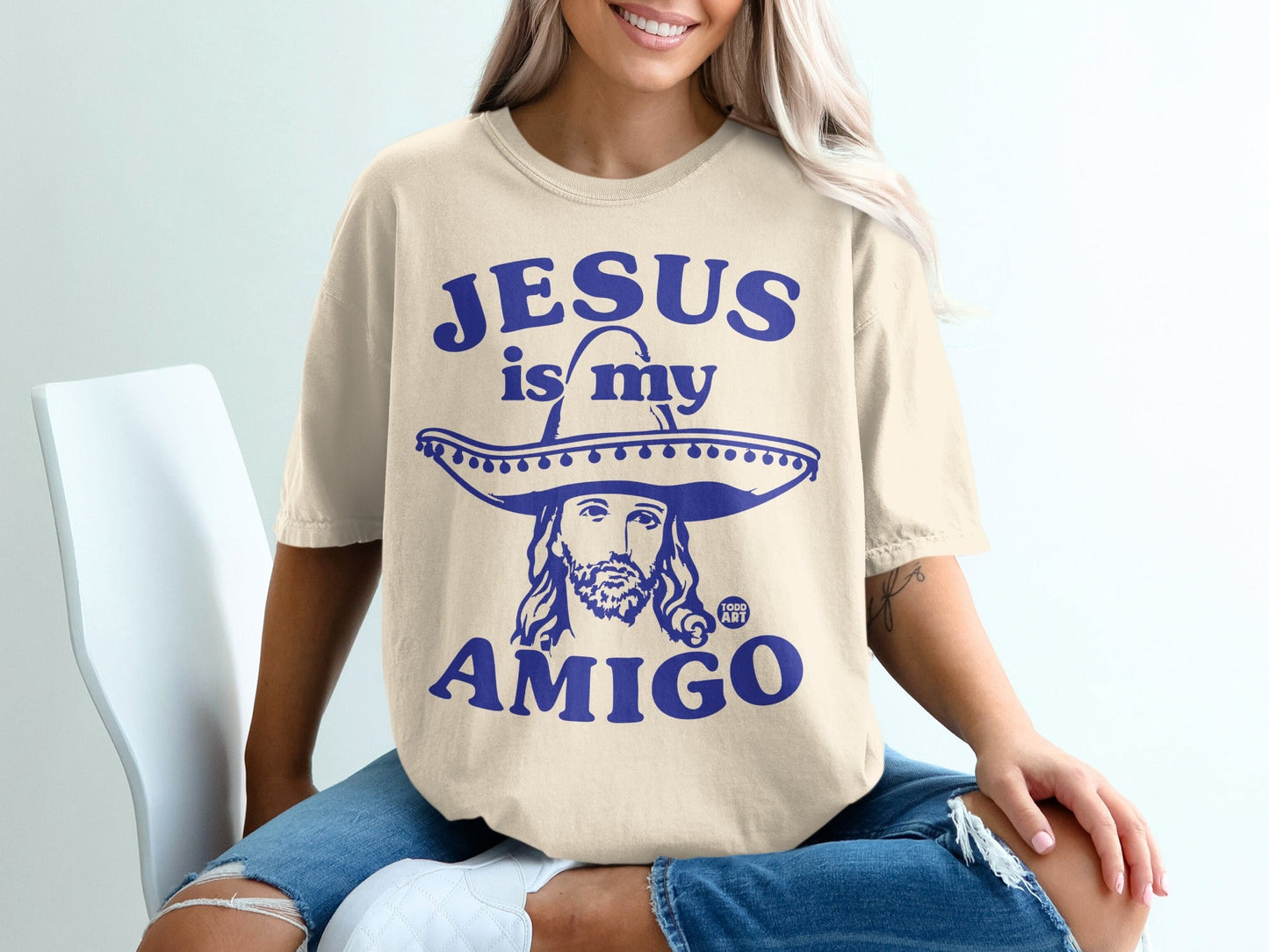 Cream t-shirt with "Jesus is my Amigo" and a sombrero-wearing Jesus graphic.