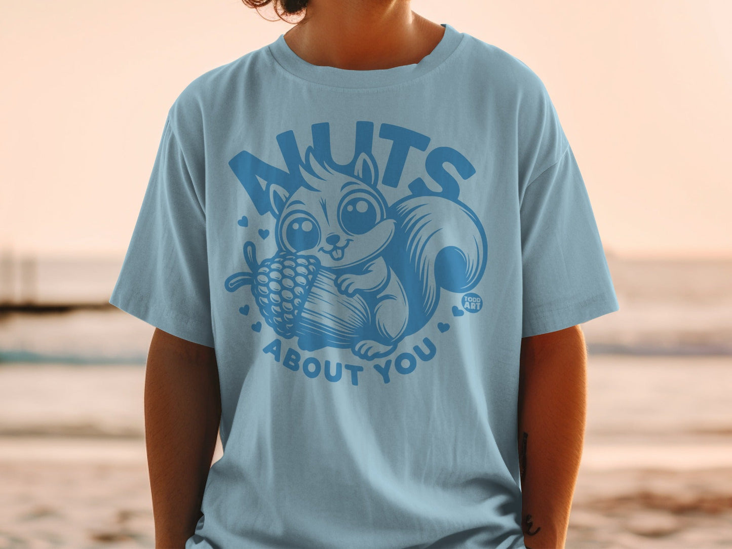 Light blue t-shirt with a cartoon squirrel holding a pinecone and the text "nuts about you".