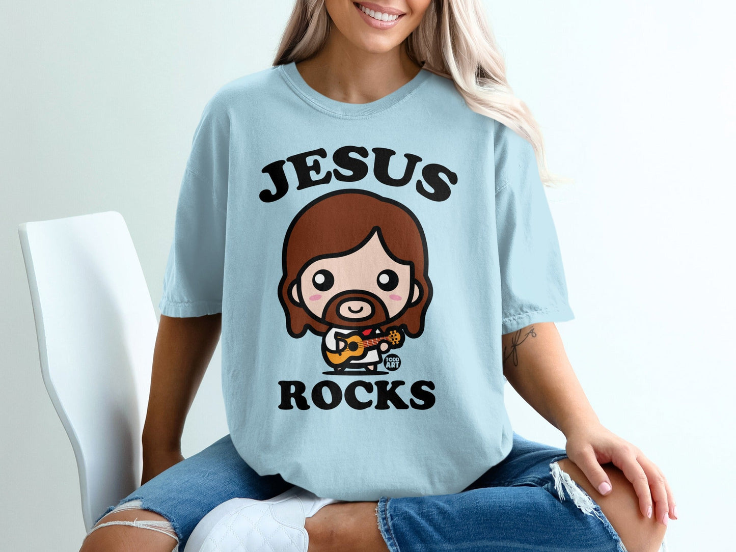 Light blue t-shirt with cartoon Jesus playing guitar, text "Jesus Rocks".