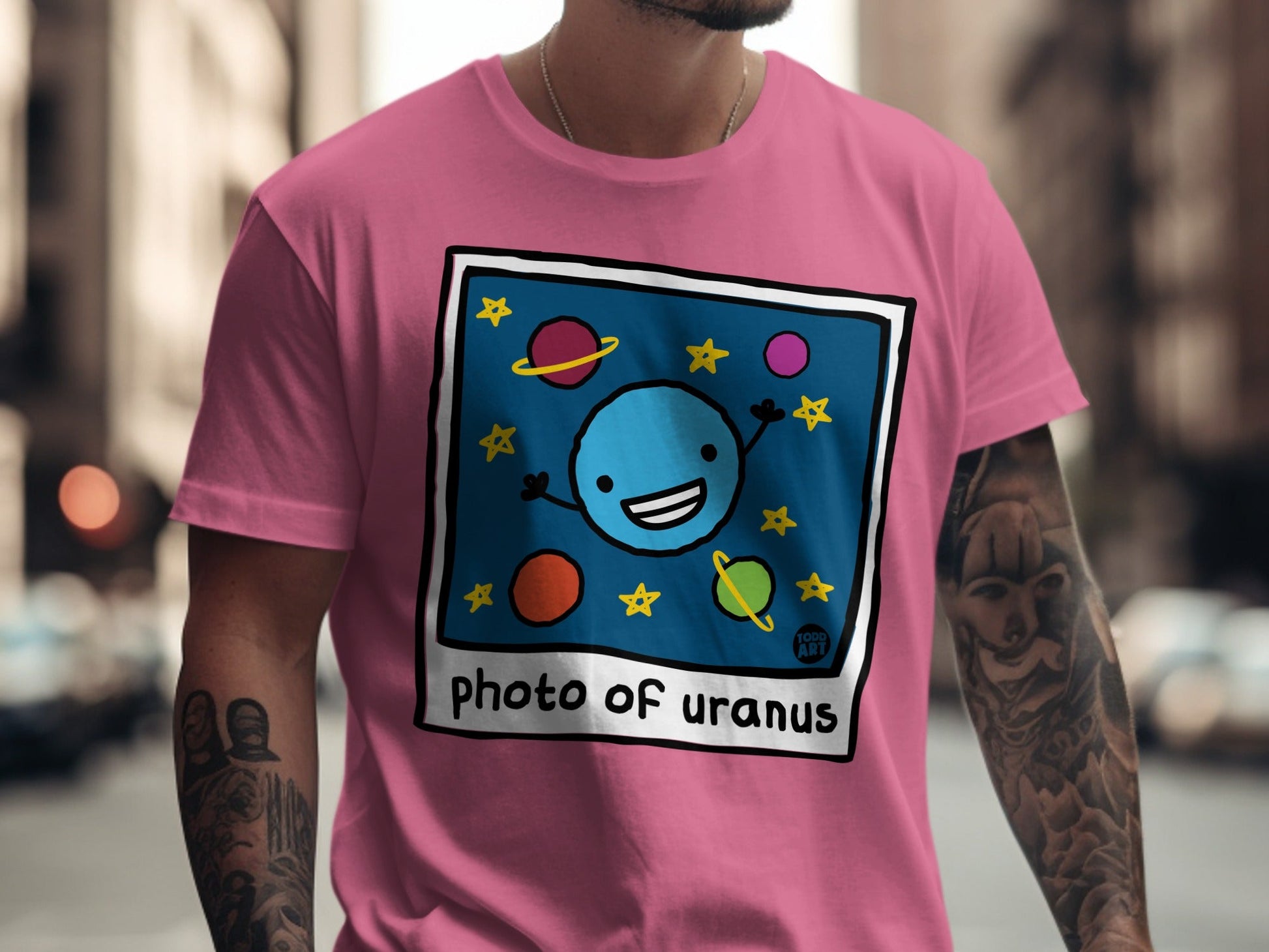 Cartoon blue Uranus with a smiley face on a pink t-shirt.