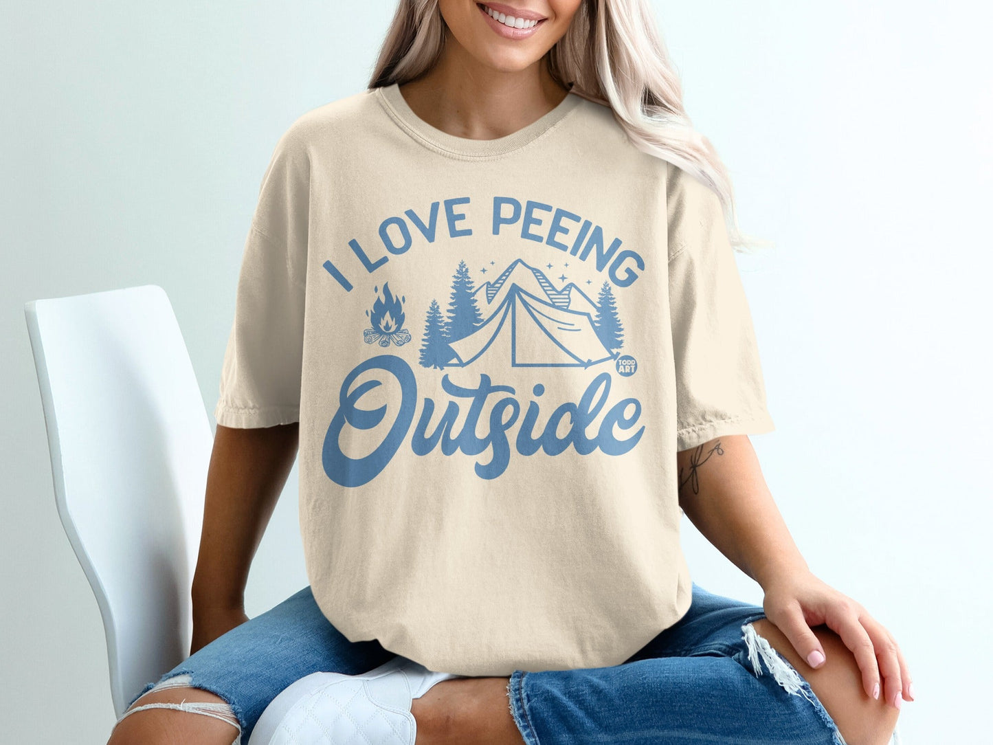 Cream t-shirt with blue text and graphics: "I love peeing outside" and a tent.