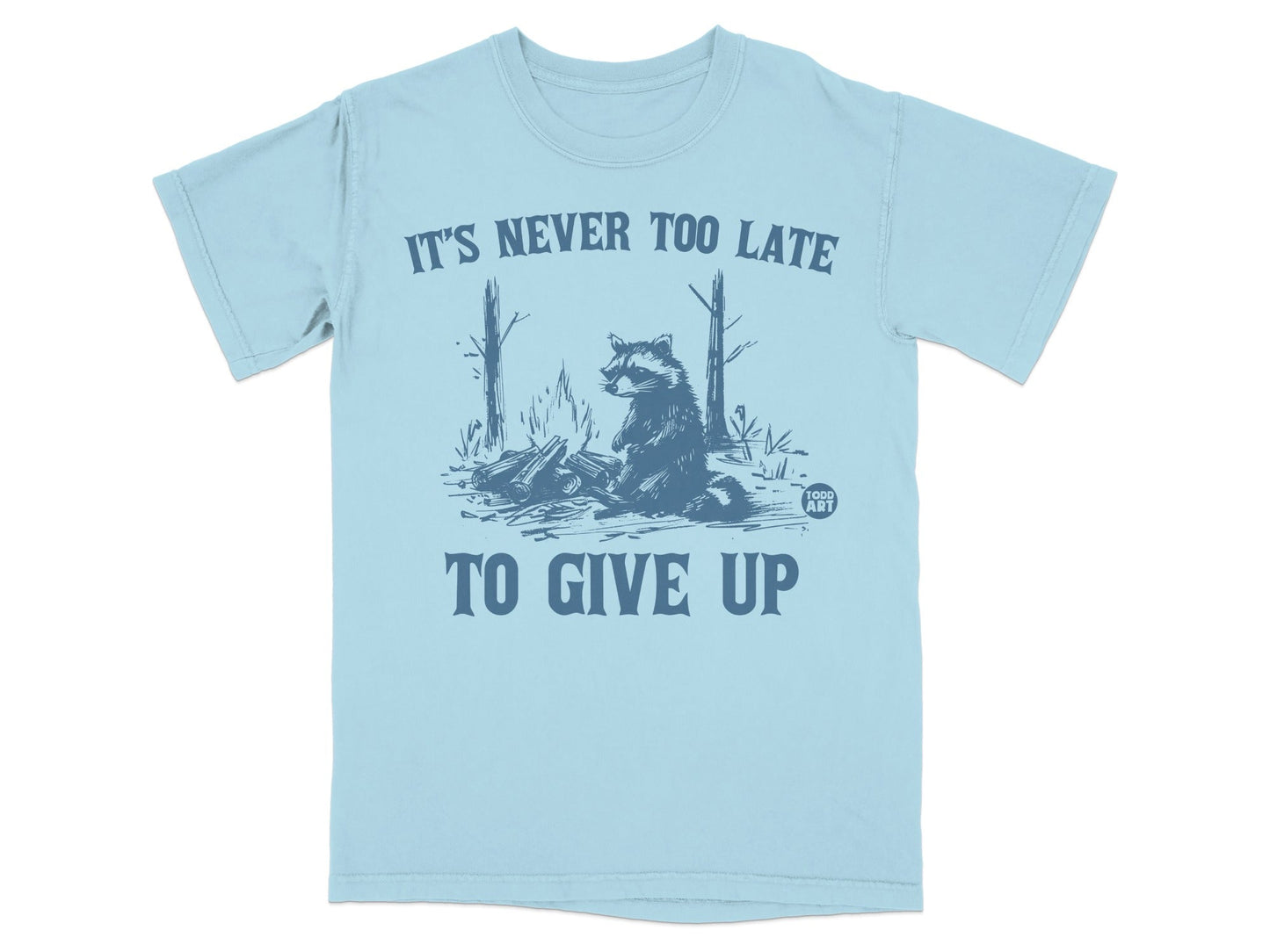 Light blue t-shirt with raccoon illustration and "IT'S NEVER TOO LATE TO GIVE UP" text.