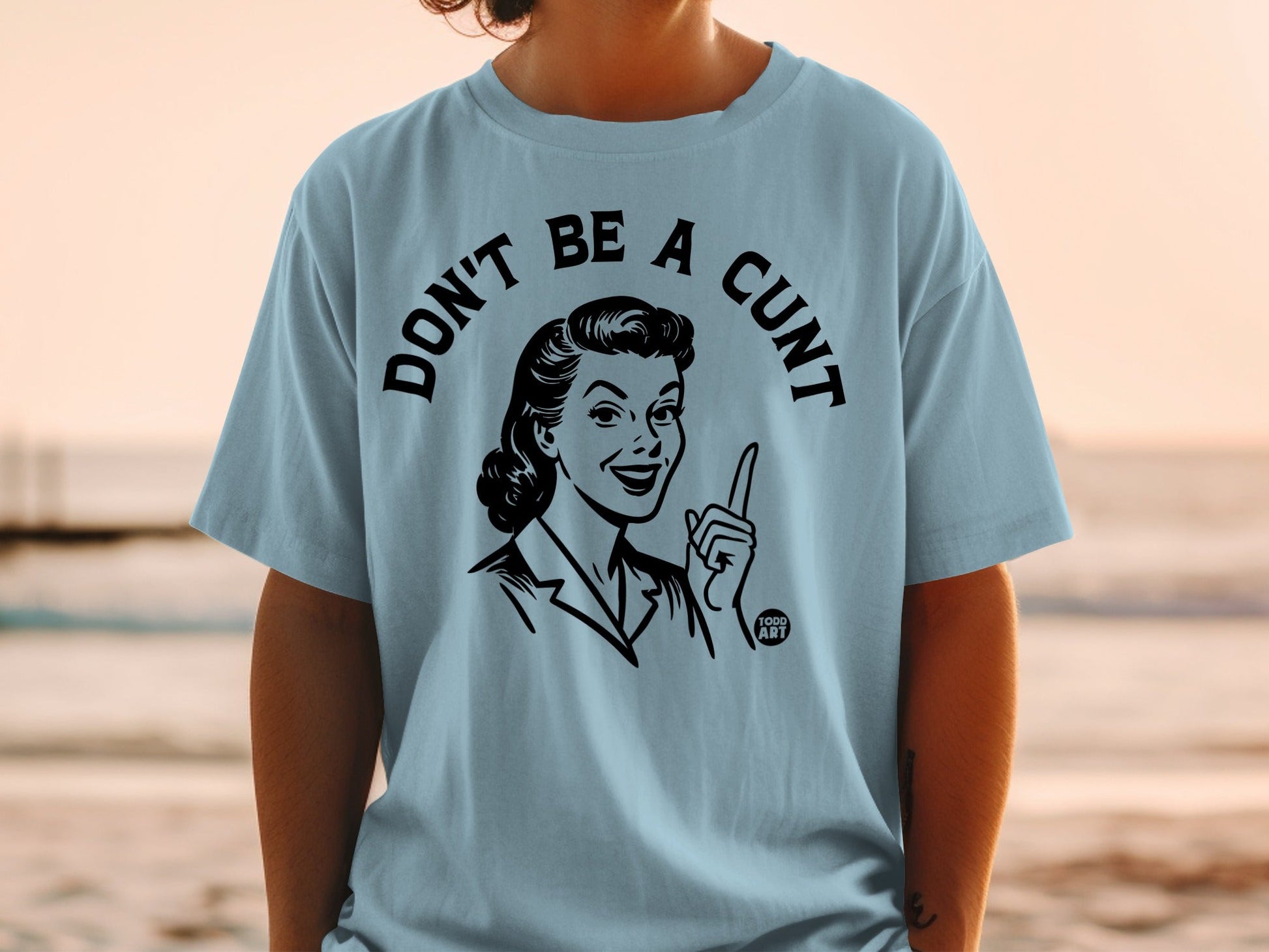 Light blue t-shirt with "DON'T BE A CUNT" and retro woman illustration.