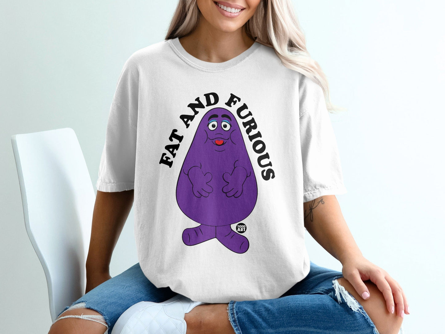 Purple Grimace character with text "FAT AND FURIOUS" on a white t-shirt.
