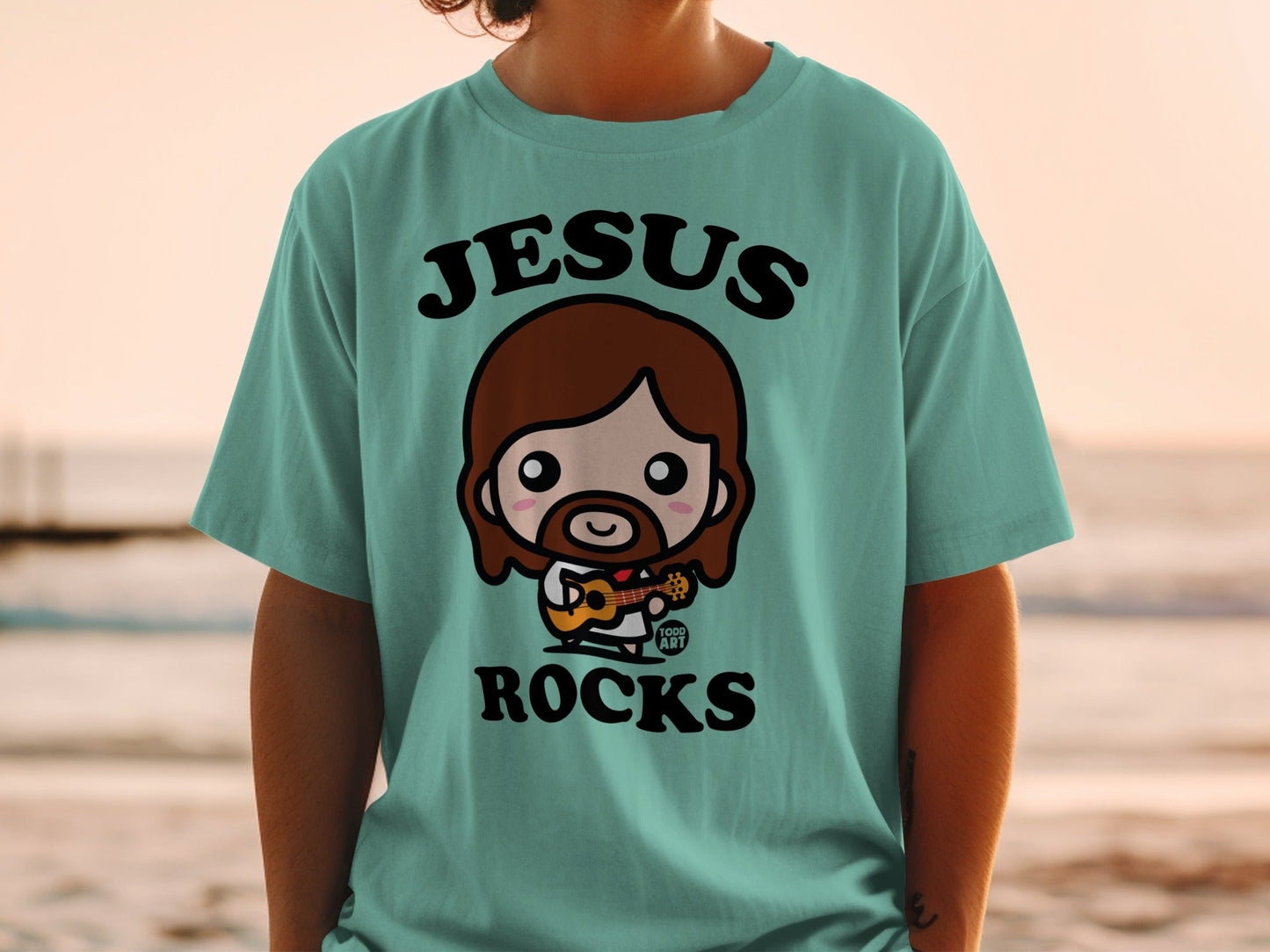 Teal t-shirt with cartoon Jesus playing guitar, text "Jesus Rocks".