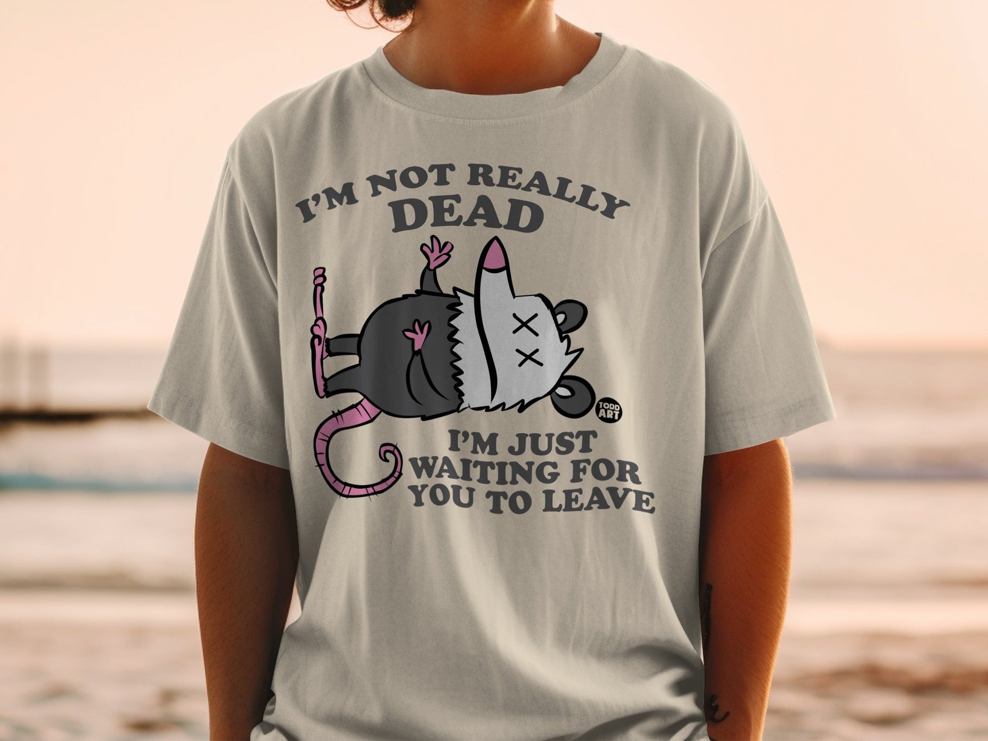 T-shirt with cartoon possum playing dead, text reads "I'm not really dead, I'm just waiting for you to leave."