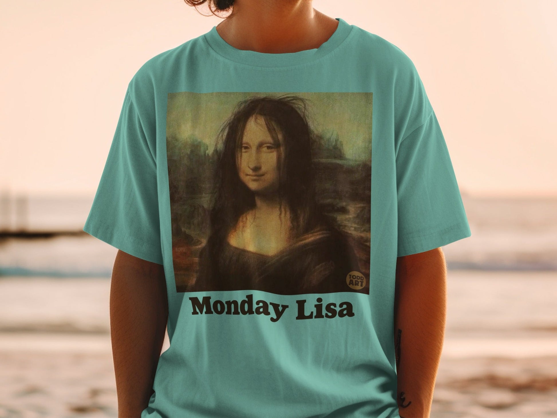 T-shirt with "Monday Lisa" and Mona Lisa artwork on teal shirt.