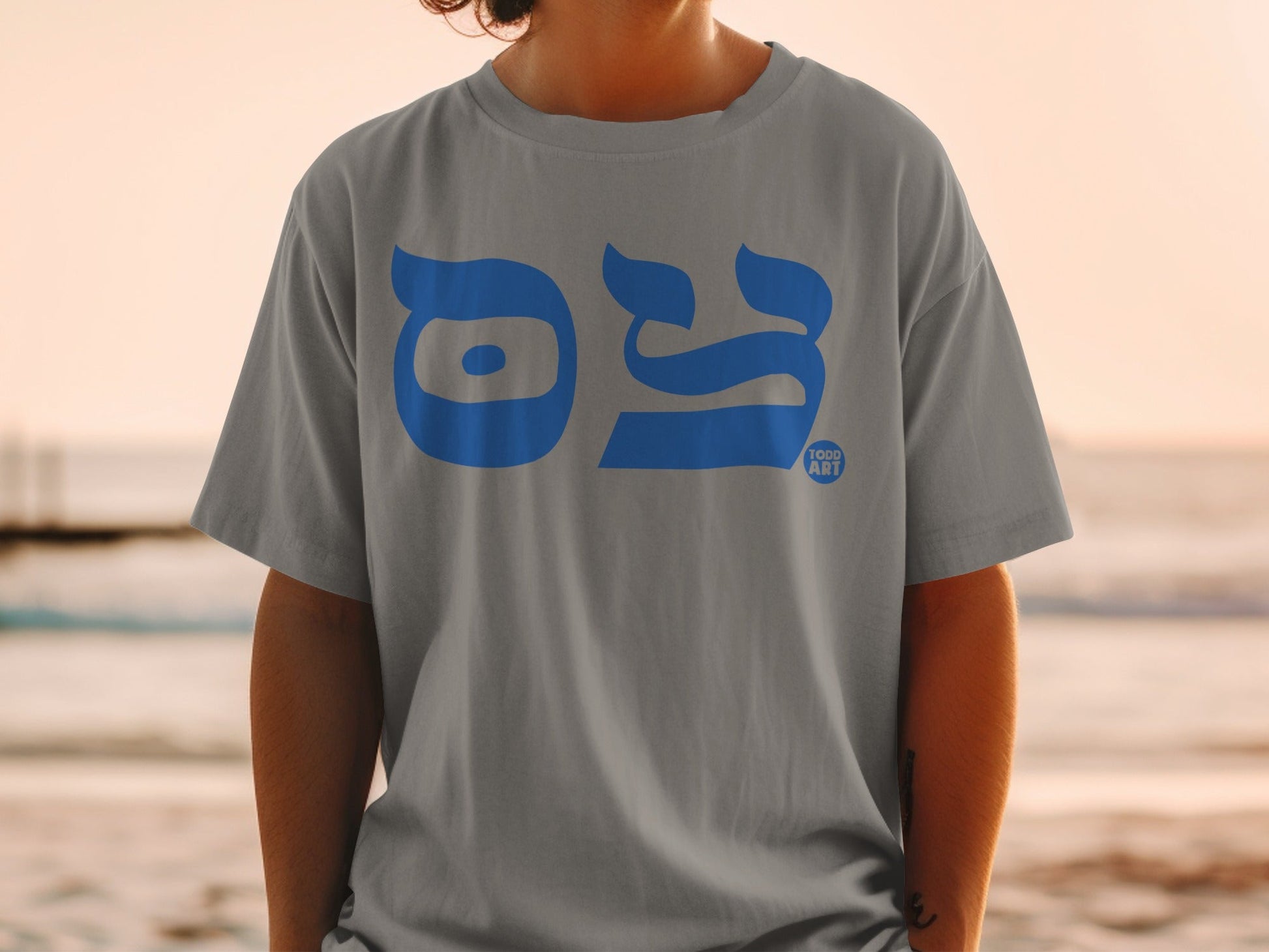 Grey t-shirt with blue Hebrew text and a small "FOOD ART" logo.