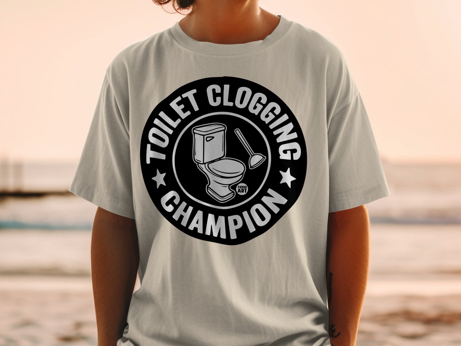 Toilet clogging champion graphic on a light gray t-shirt.